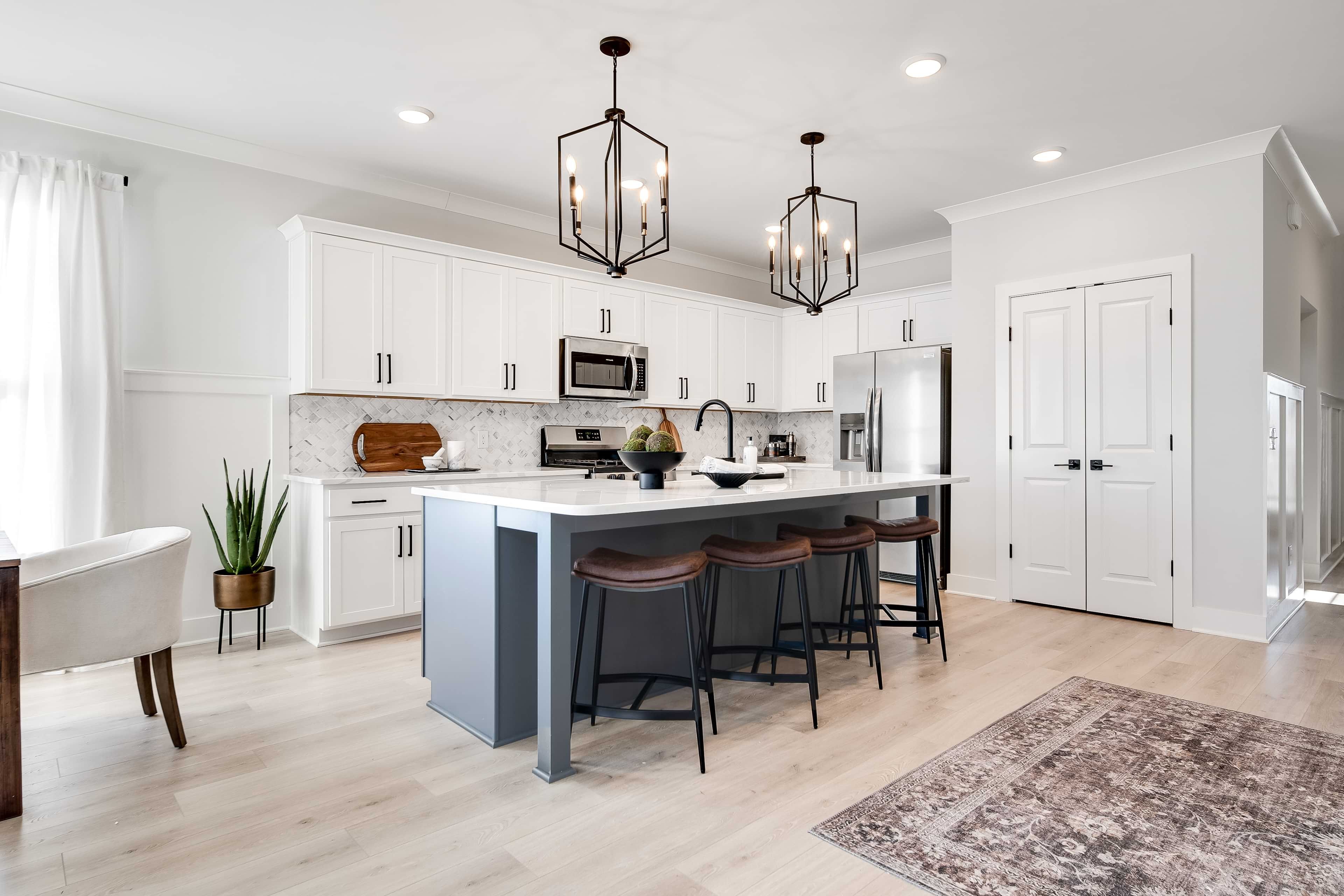 Modern Kitchen with Island and Pendant Lights in Richvale Estates Modern kitchen with white cabinets, marble backsplash, and island. Pendant lights, hardwood floors in Richvale Estates.