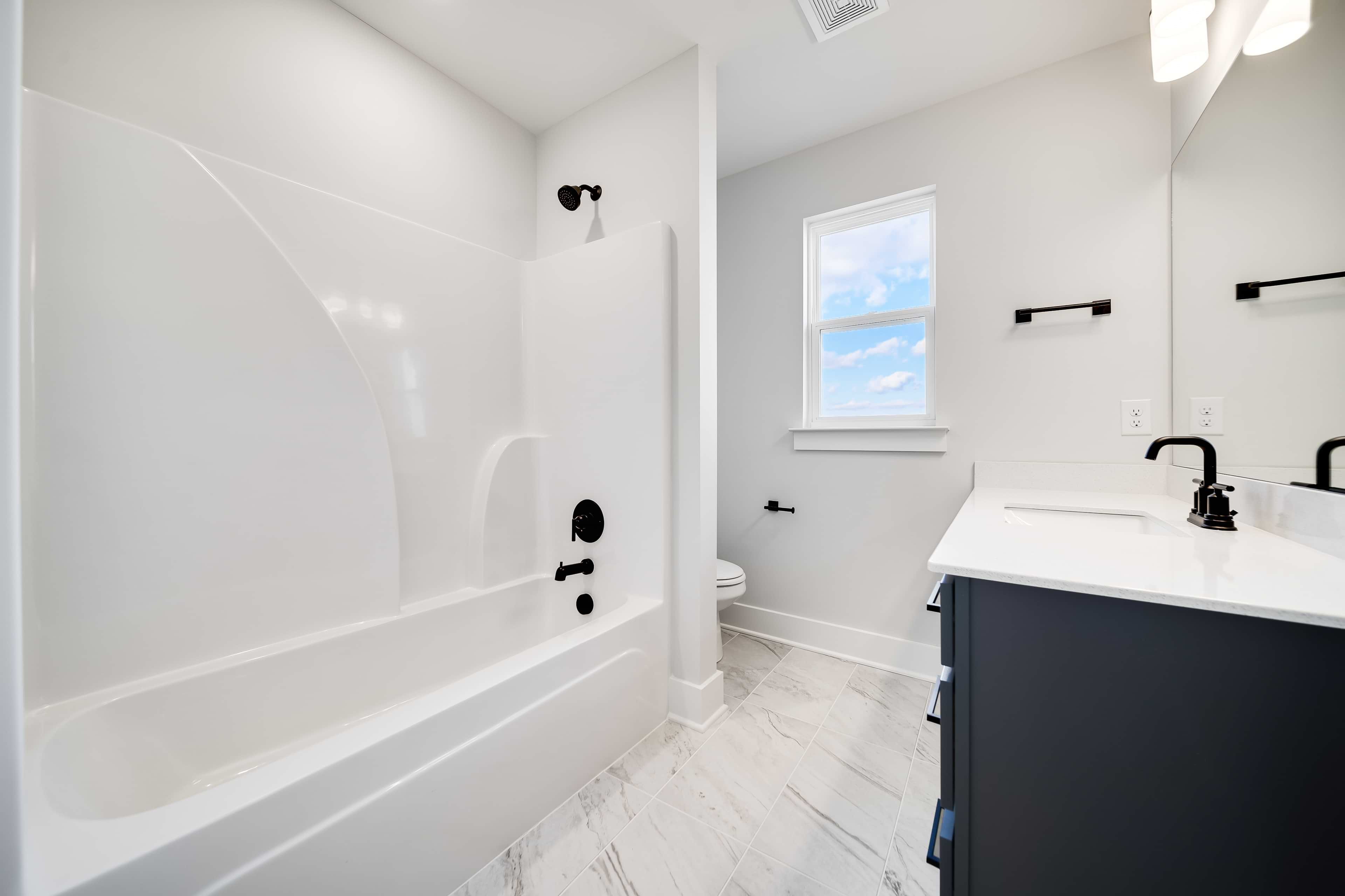 Modern Bathroom with Marble Tile in Richvale Estates Modern bathroom with white tub, black fixtures, marble tile floor in Richvale Estates.