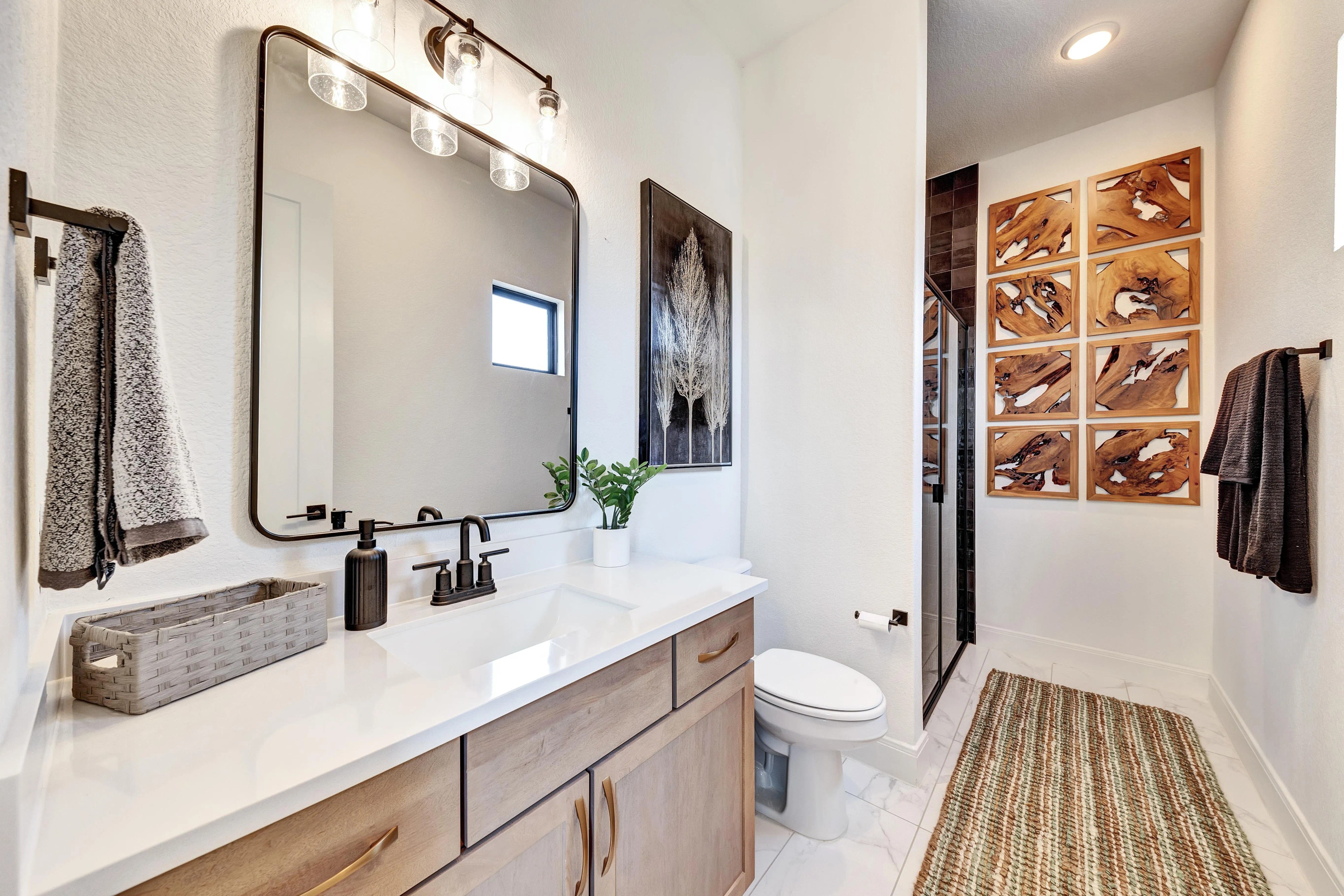 Modern Bathroom Design in Hawkes Landing Home Elegant bathroom features large mirror, wood vanity, artwork, in upscale Hawkes Landing home.