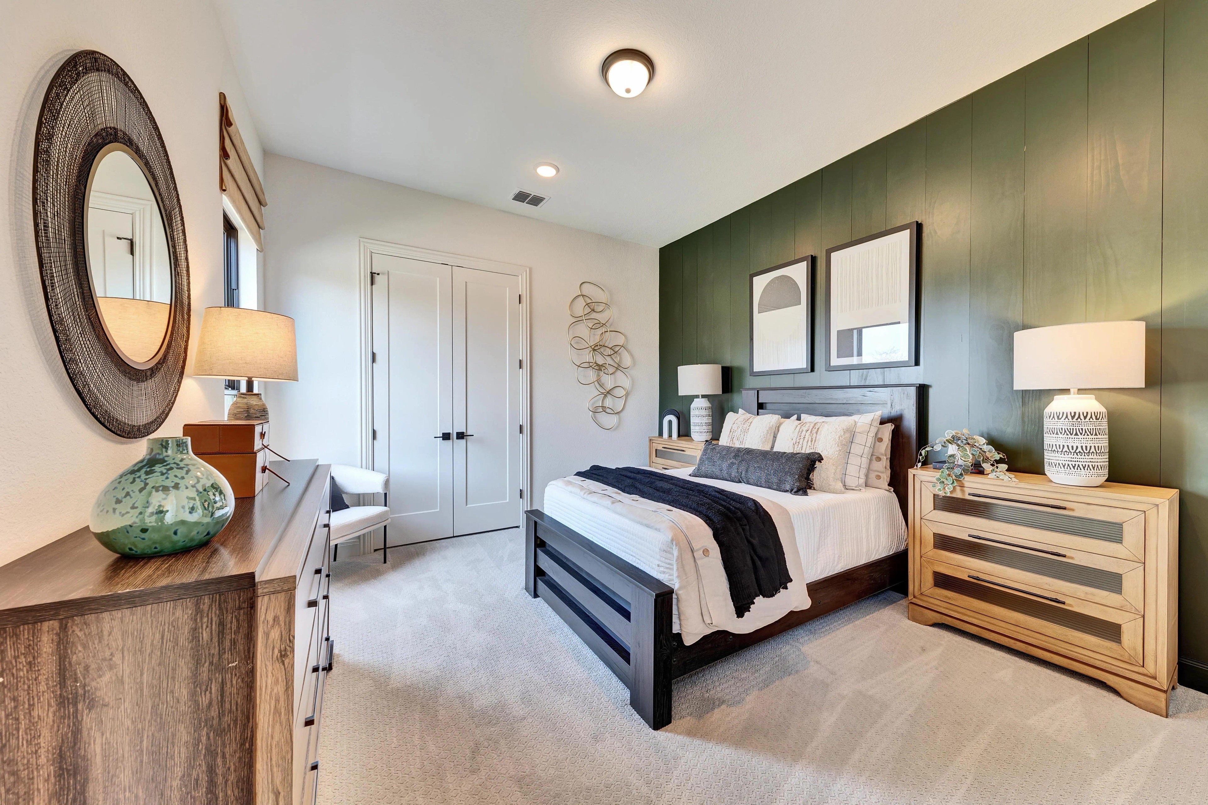 Modern Bedroom Design in Hawkes Landing with Green Accent Wall Modern bedroom with dark wood bed, dual nightstands, green accent wall, wall art, and round mirror in Hawkes Landing.