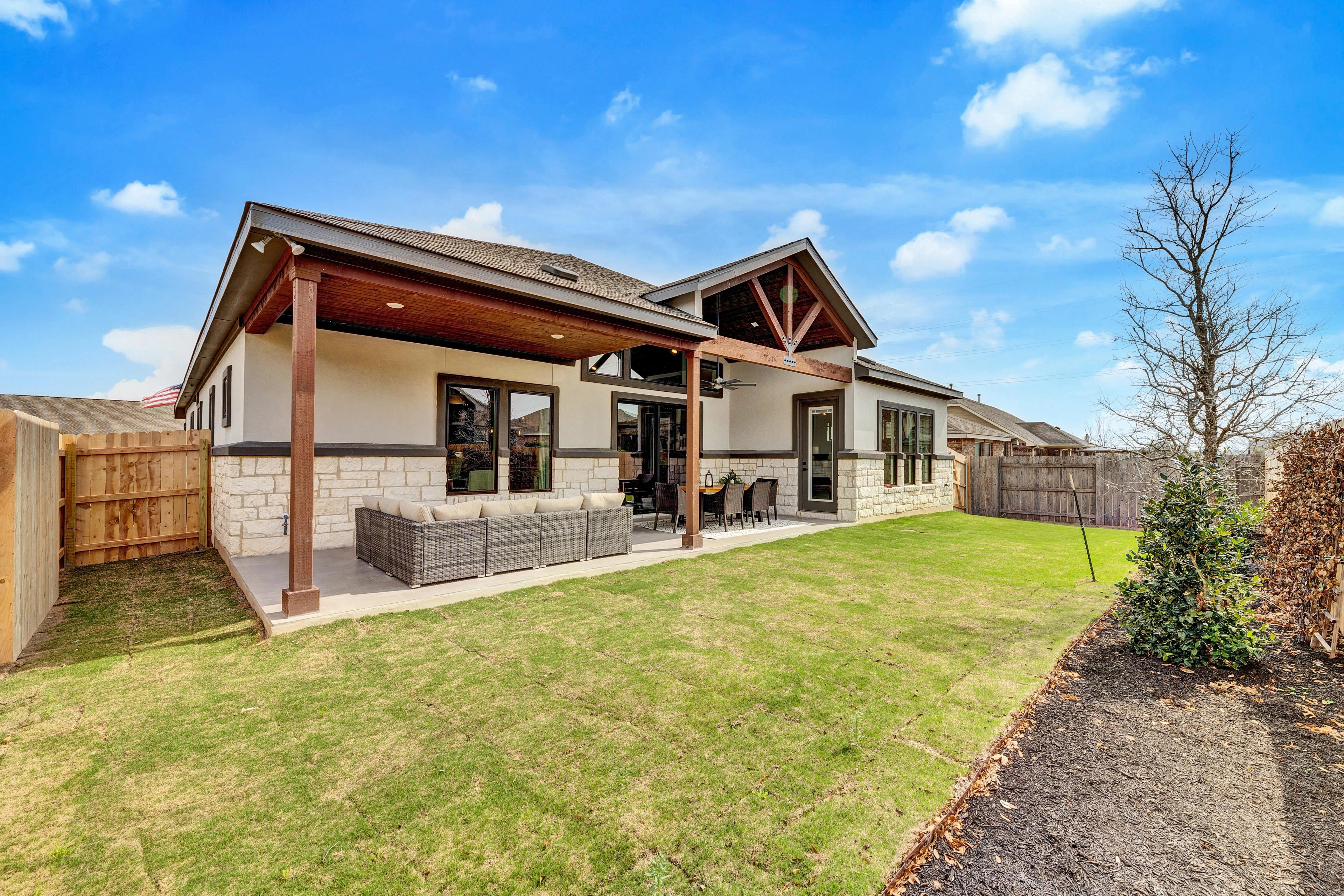 Modern Home with Stone Exterior in Hawkes Landing, Texas Modern home with stone and wood exterior, covered patio, and landscaped yard in Hawkes Landing, Texas.