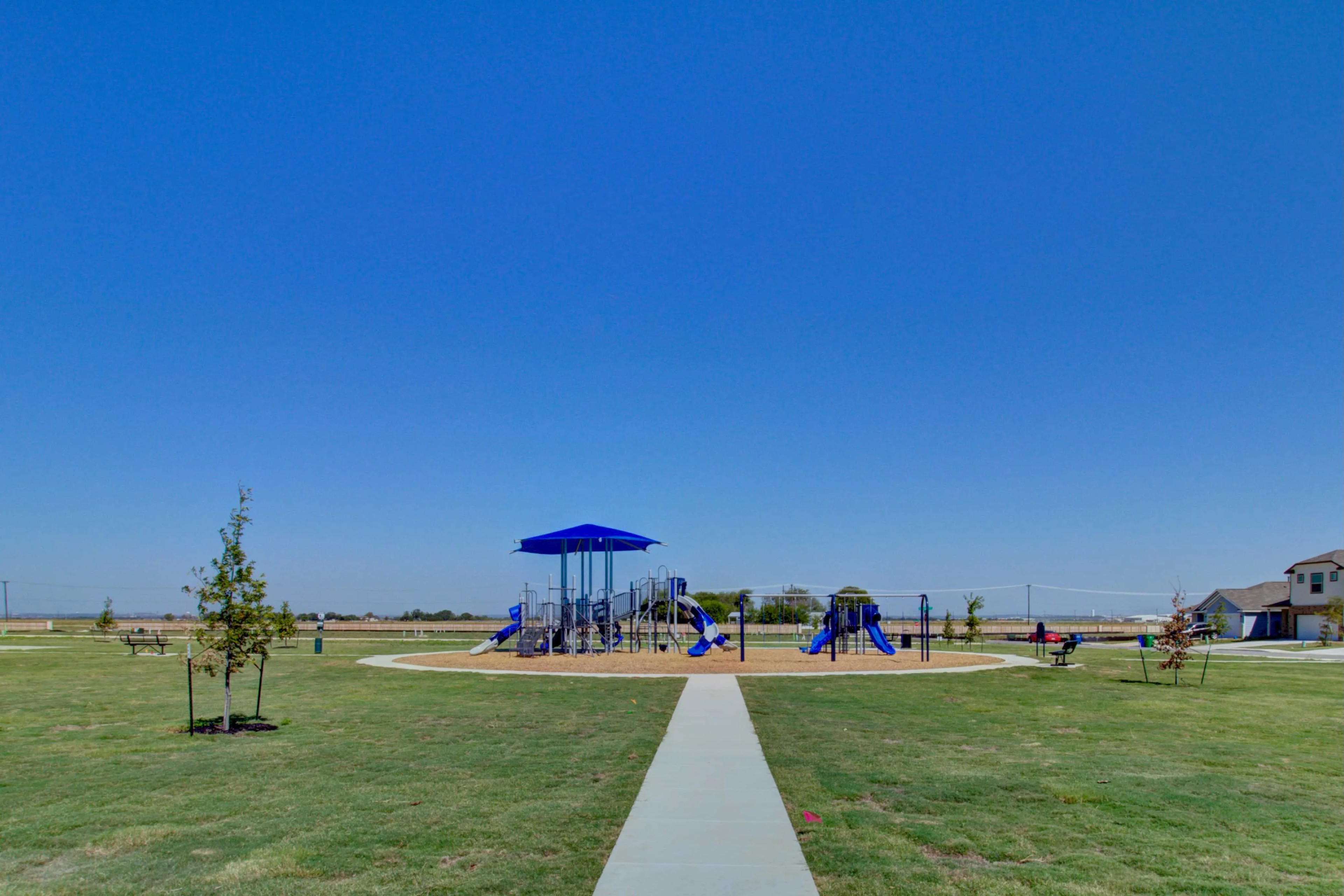 Playground at Dauer Ranch Community, Texas Playground with blue equipment on lush lawn in Dauer Ranch community, Texas. Clear sky backdrop.