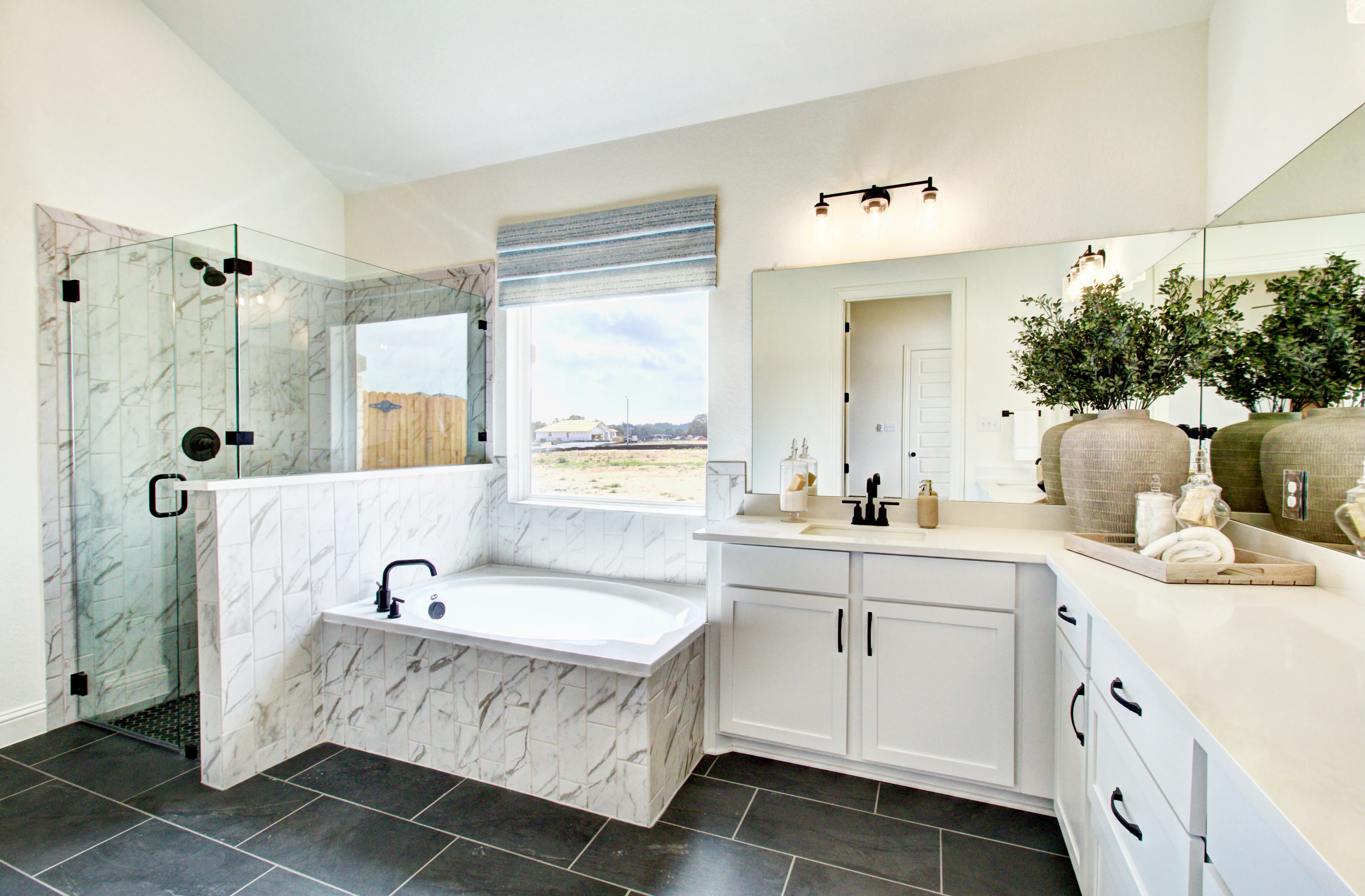 Luxury Bathroom Design in Veranda Community Modern bathroom with marble tiles, glass shower, large window, and white cabinets in Veranda community.
