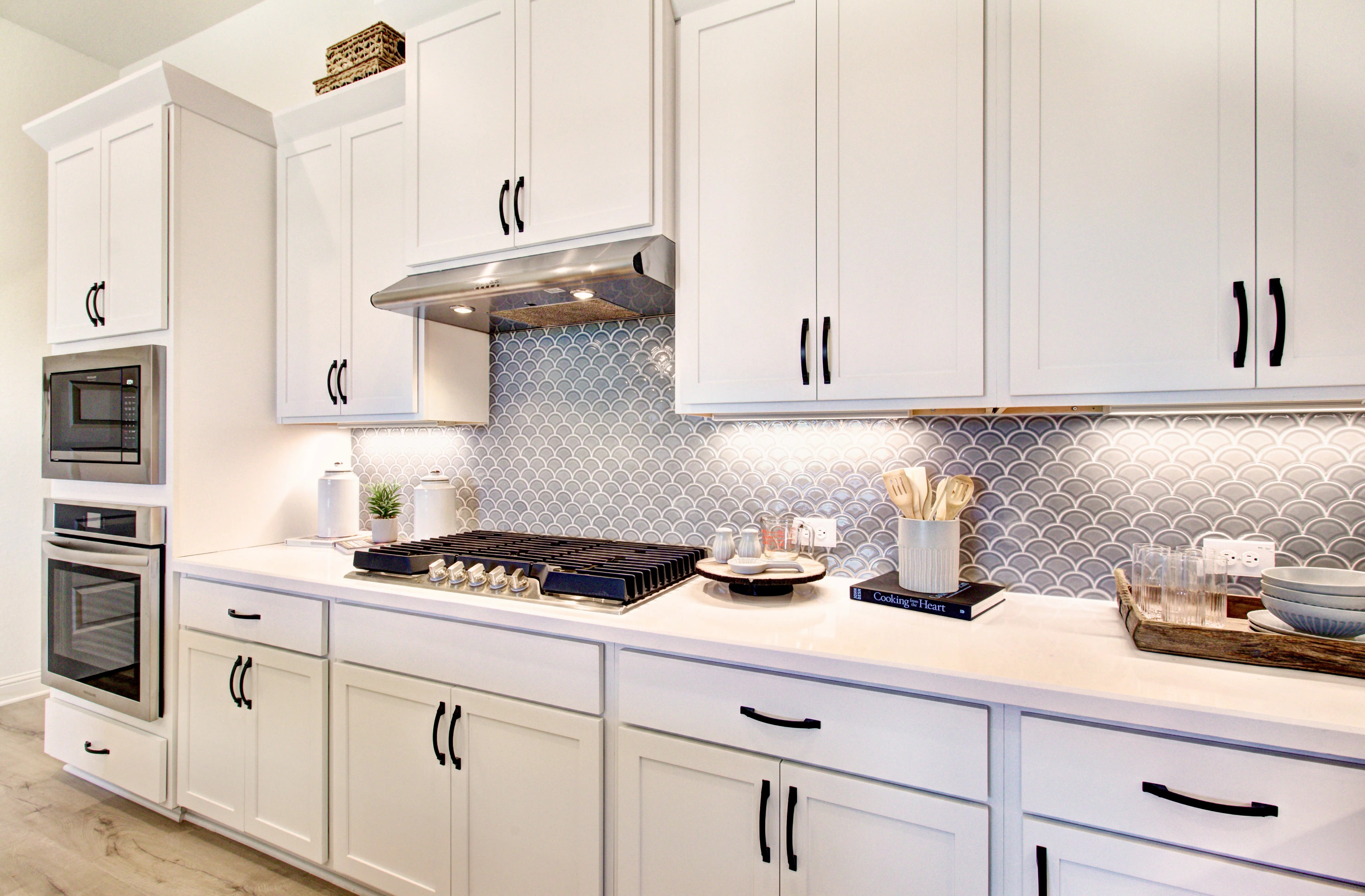 Modern Kitchen Design in Veranda Community with Elegant Features Modern kitchen in Veranda community with white cabinets, fish scale tile backsplash, and luxury appliances.