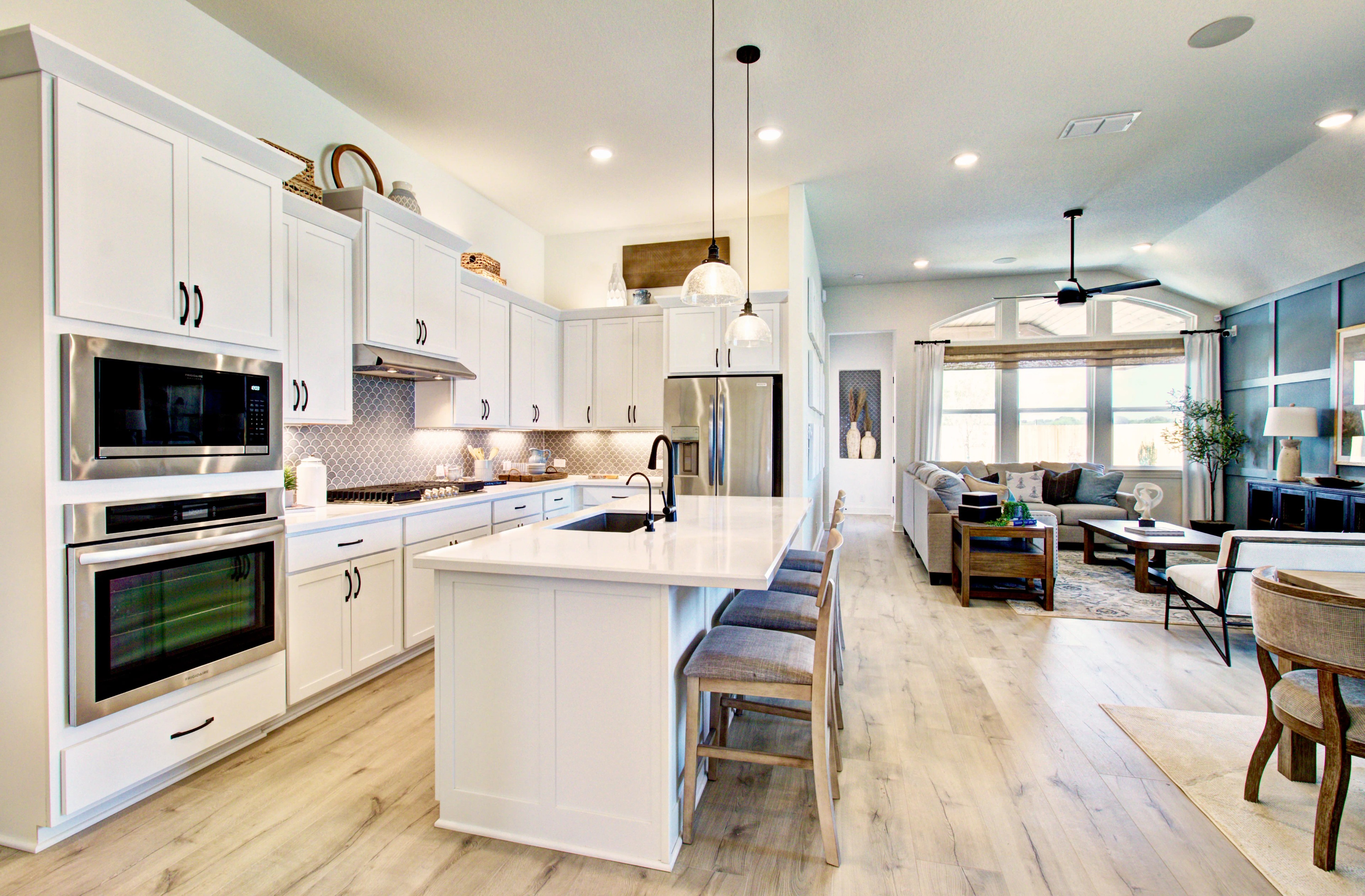 Kitchen and Living Area with Modern Design in Veranda Community Modern kitchen-living room with high ceiling, island, white cabinets, stainless appliances in Veranda community home.