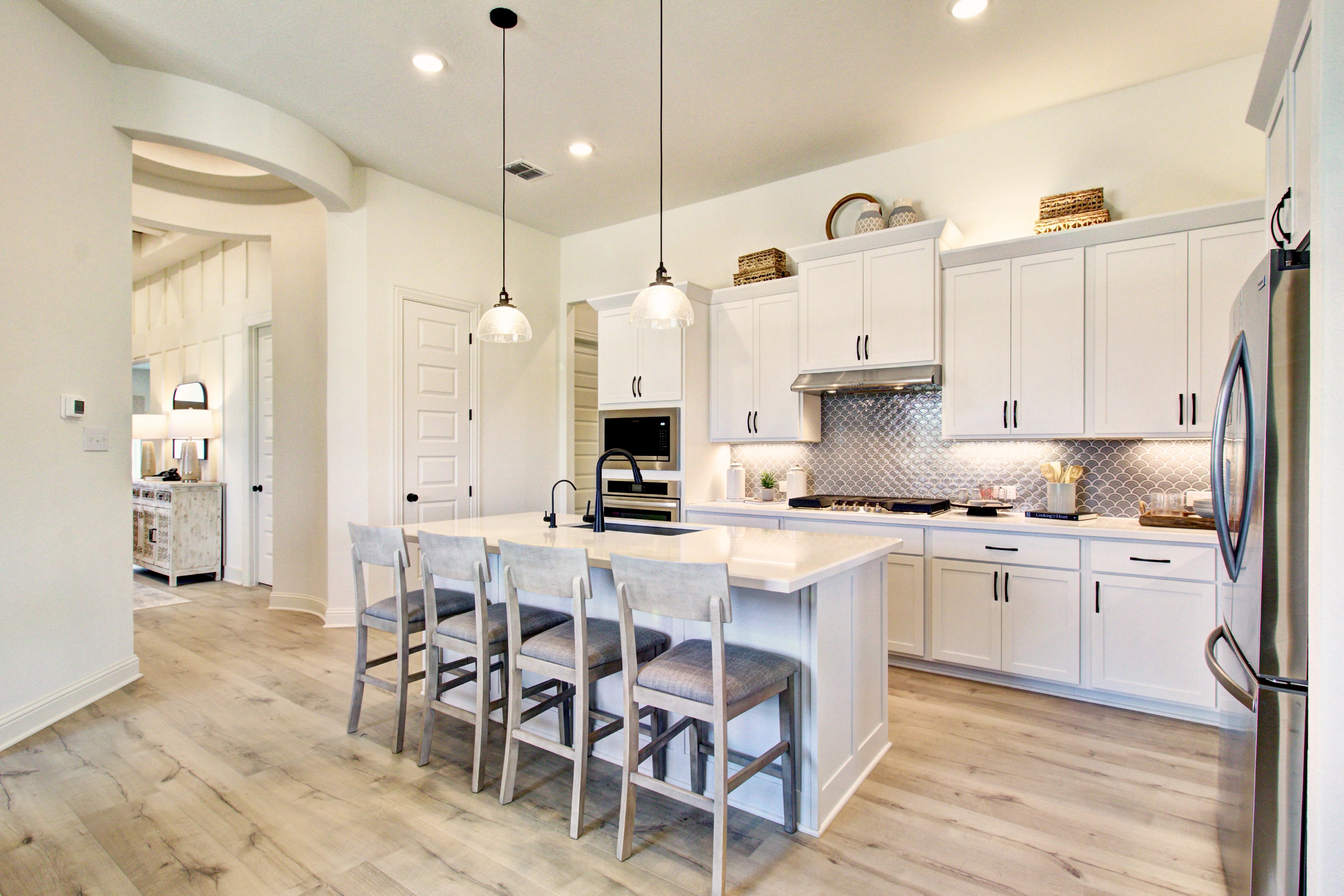 Veranda Community Kitchen with Elegant White Cabinetry Modern kitchen in Veranda community with white cabinetry, pendant lights, and island seating.