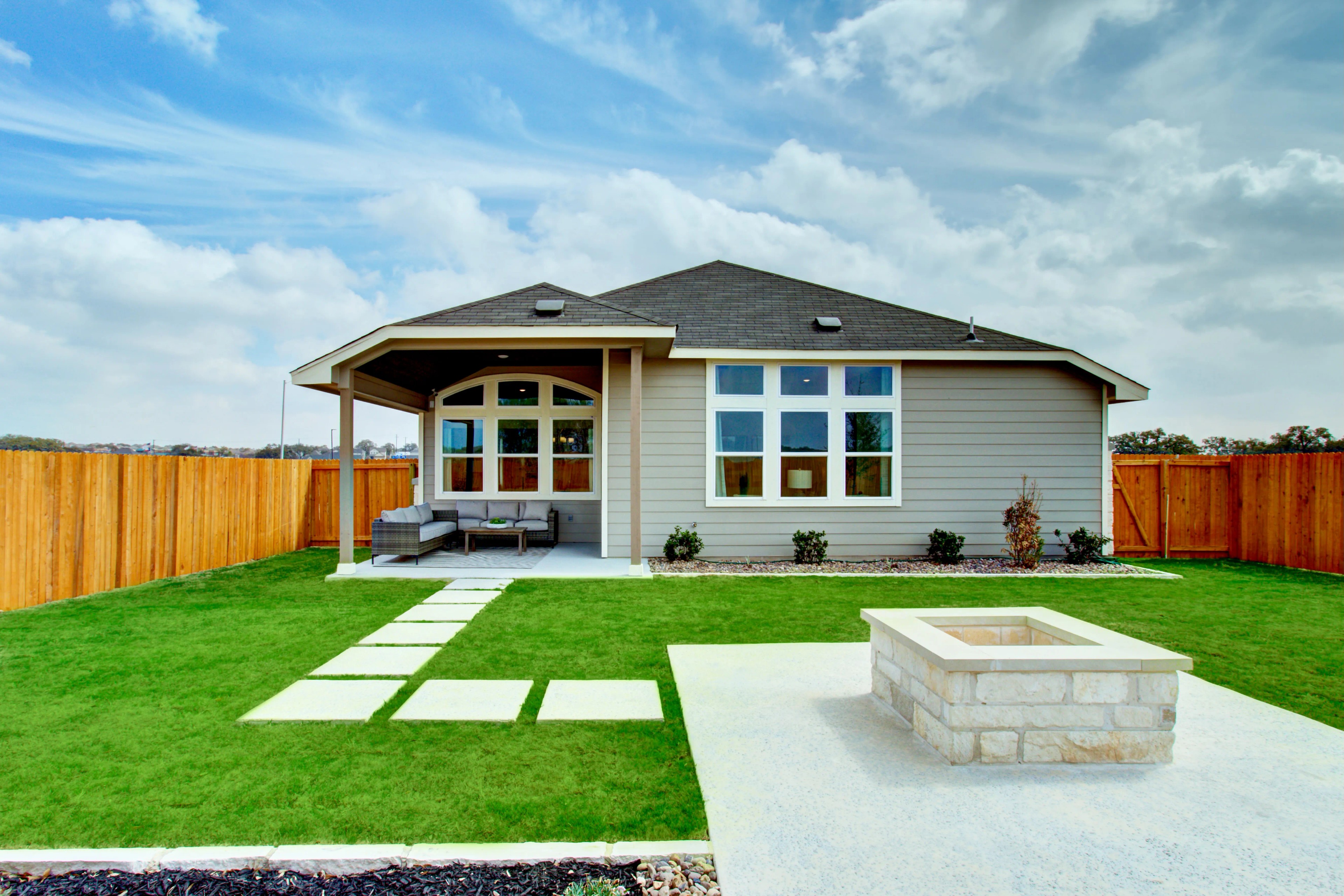 Modern Home with Veranda and Fire Pit in Veranda Community Modern house with gray siding, large windows, veranda, fire pit, in fenced yard. Veranda community.