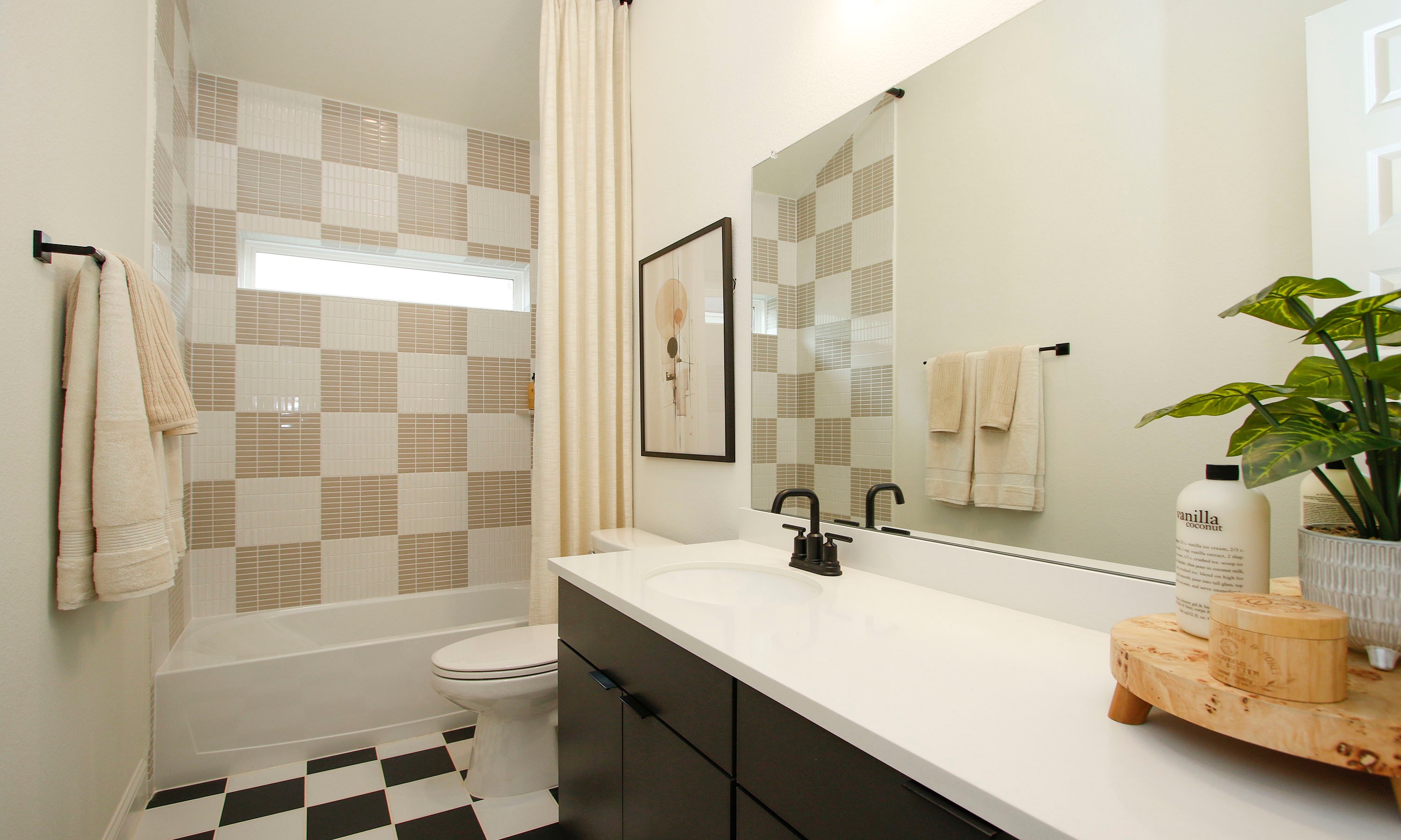 Modern Bathroom Design in The Woodlands Hills with Checkered Tiles Chic bathroom with checkered tiles, modern fixtures, large mirror, and plant decor in The Woodlands Hills.