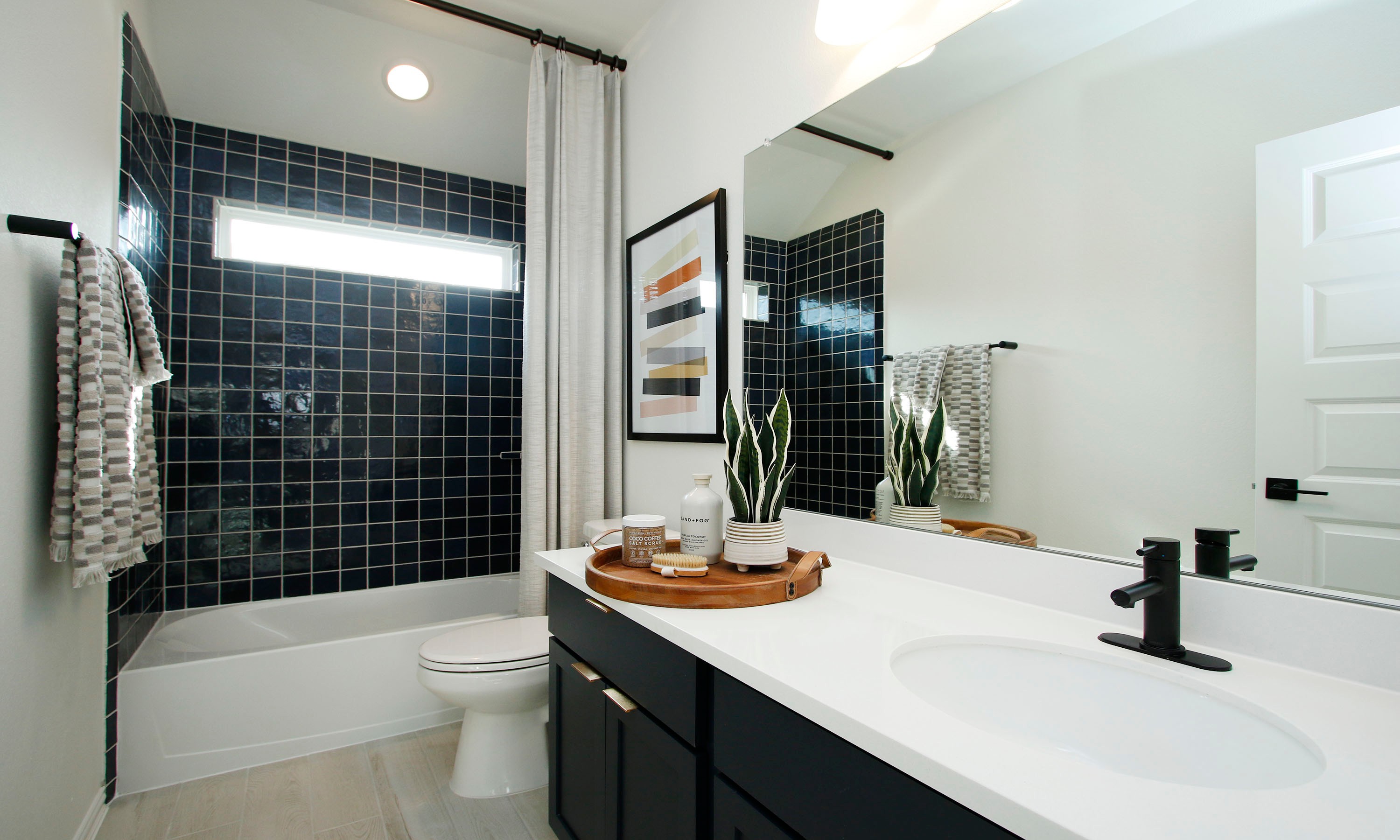 Woodlands Hills Modern Bathroom with Sleek Black Tile Modern bathroom with black tile, white countertop, plant decor, in Woodlands Hills community.
