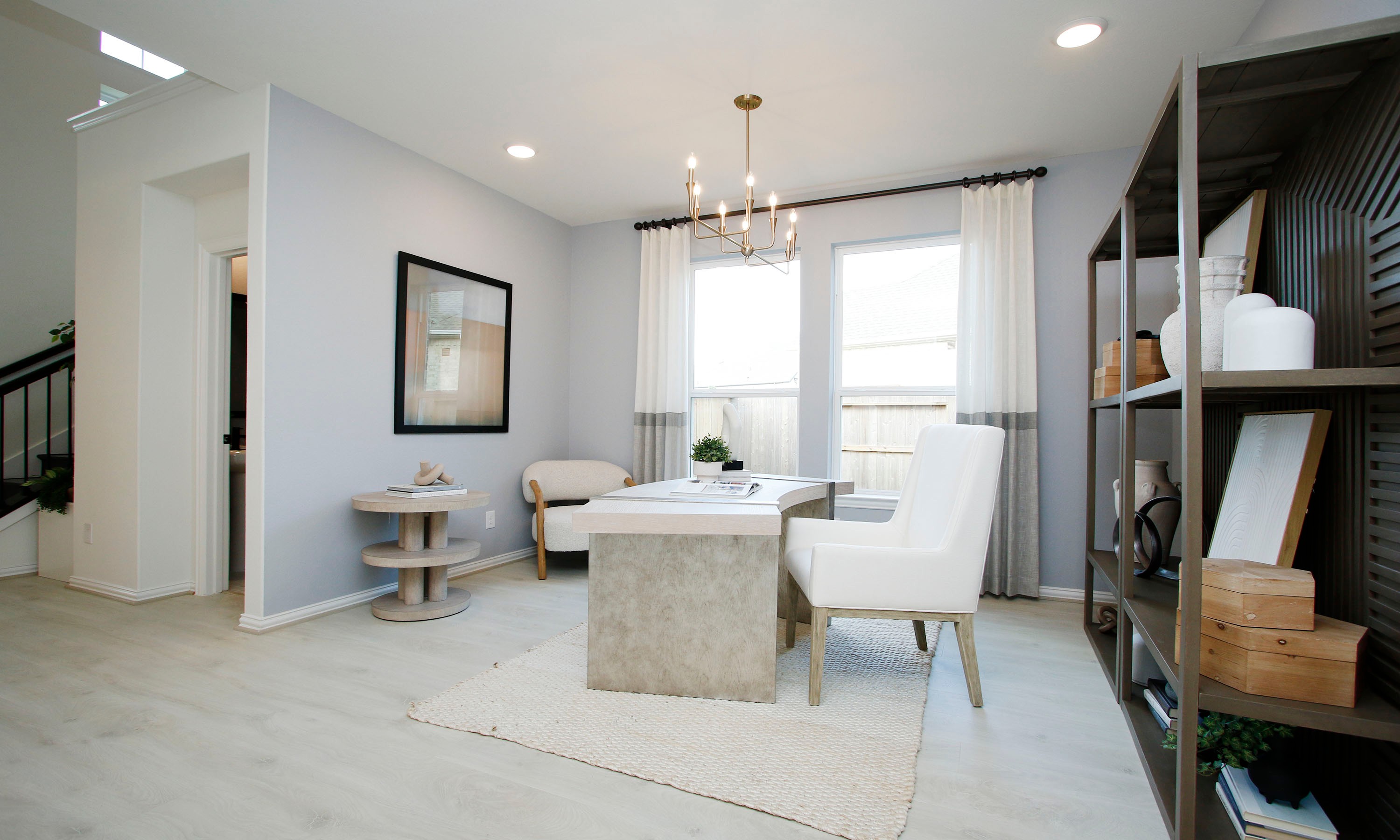 Elegant Home Office at The Woodlands Hills with Chandelier and Shelving Modern home office with chandelier, large windows, light walls, and shelving in The Woodlands Hills community.