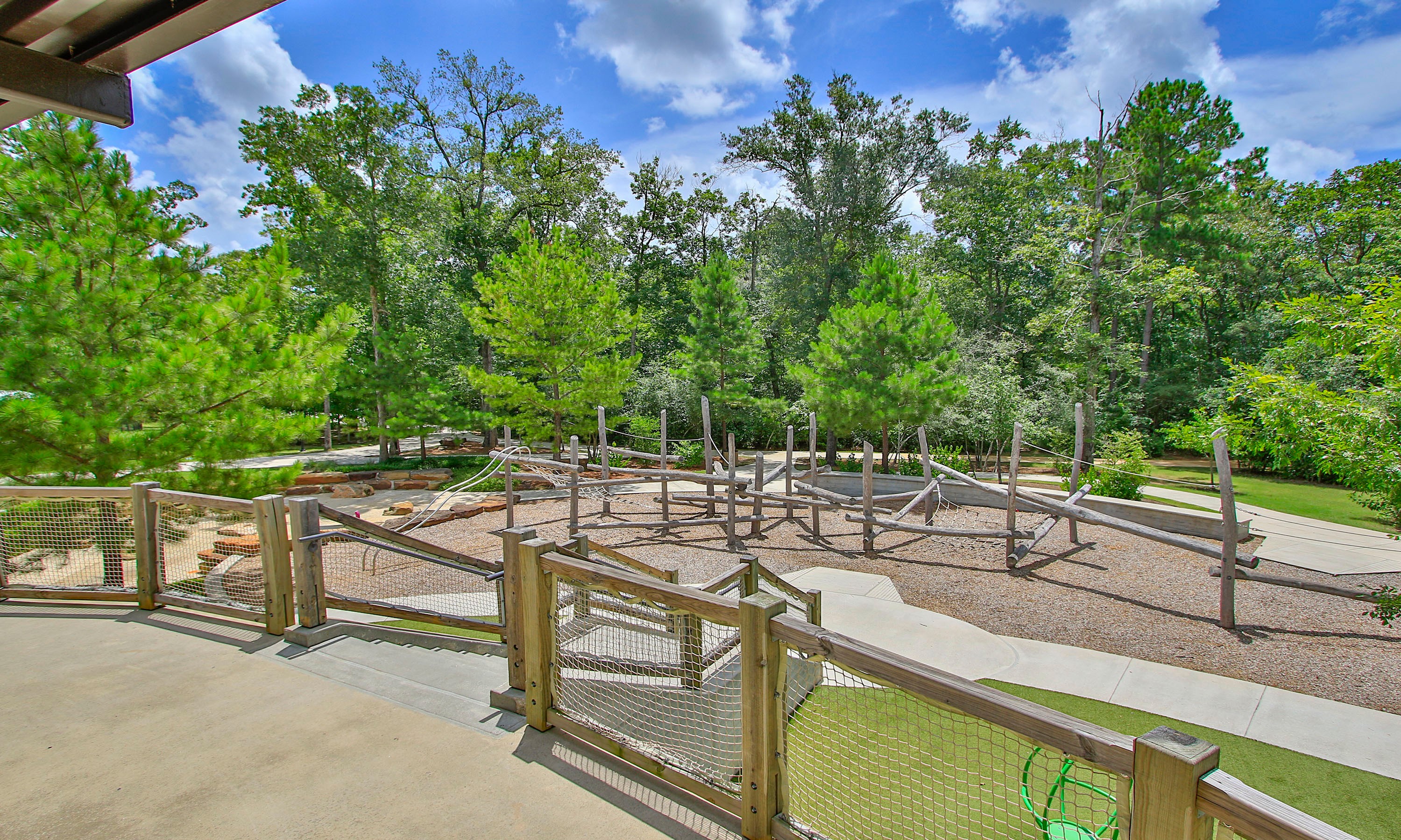 The Woodlands Hills Playground with Wooden Climbing Structures Natural wood playground in lush forest setting, The Woodlands Hills, with wooden climbing structures.