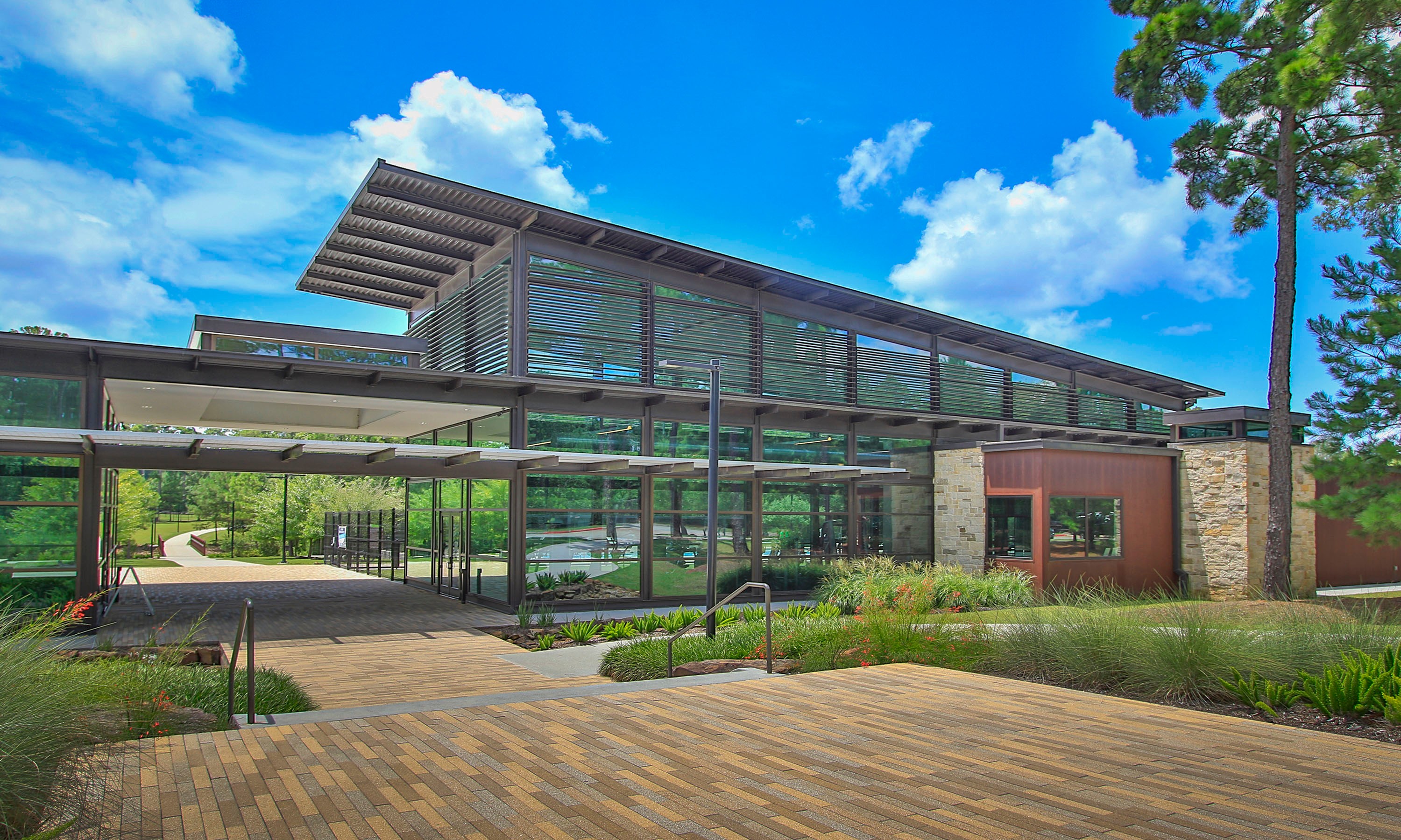 Modern Architecture in The Woodlands Hills Community Modern community building with glass walls and louvered panels, set in lush greenery, The Woodlands Hills.