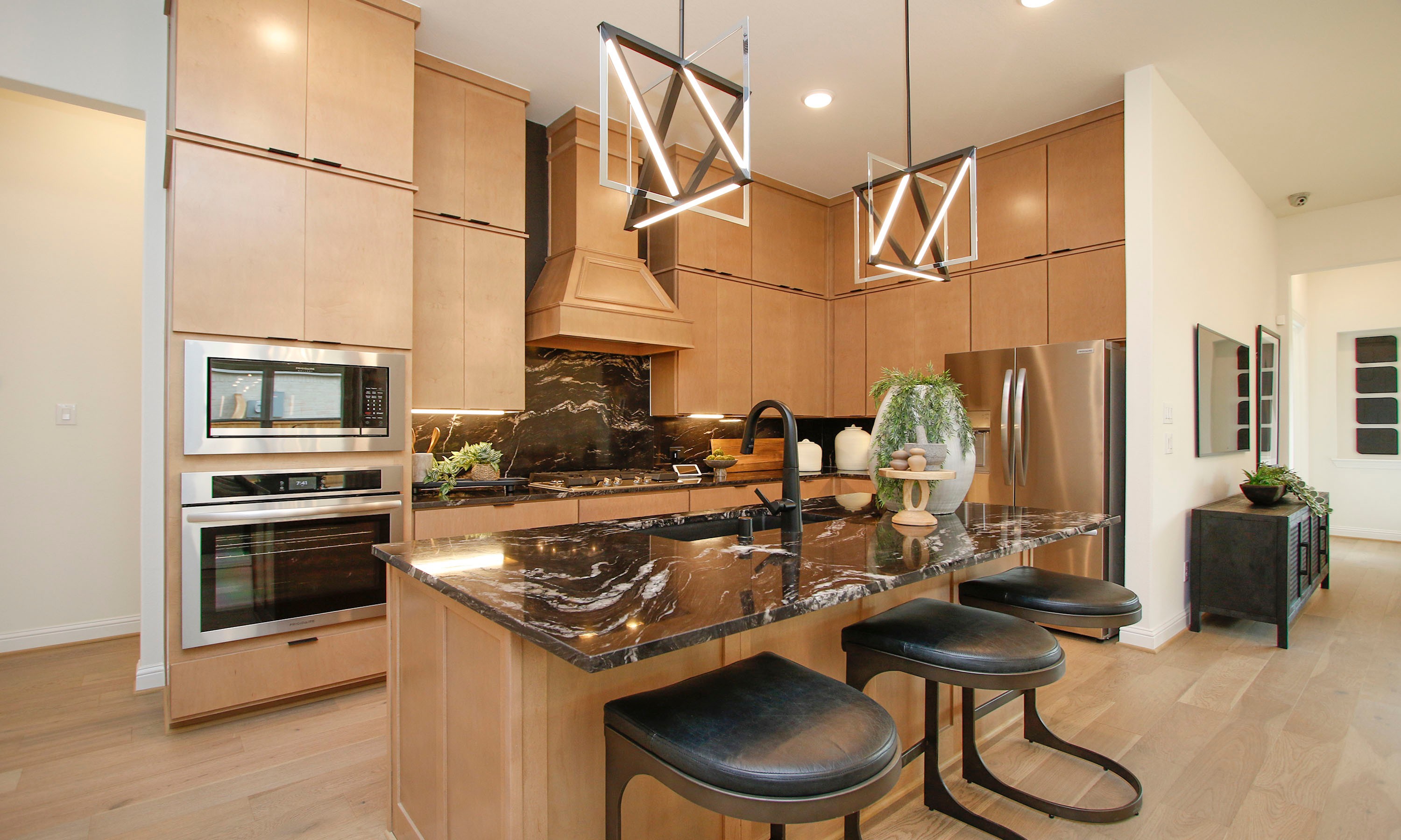 Modern Kitchen with Wood Cabinets and Marble in Woodlands Hills Luxury Woodlands Hills kitchen with modern wood cabinets, black marble counters, geometric lighting, stainless appliances.