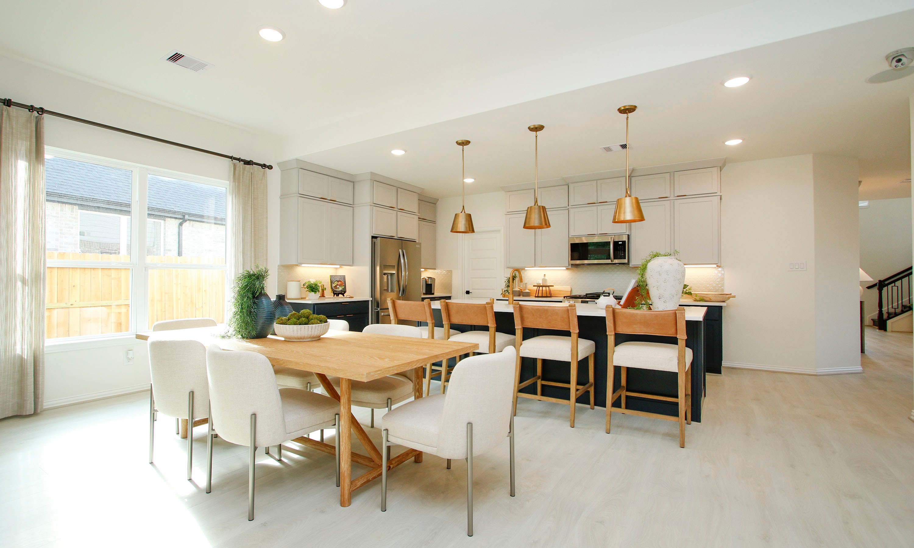 Modern Kitchen and Dining in The Woodlands Hills with Elegant Design Modern kitchen and dining area with pendant lights, light wood floors, and sleek cabinetry in The Woodlands Hills.