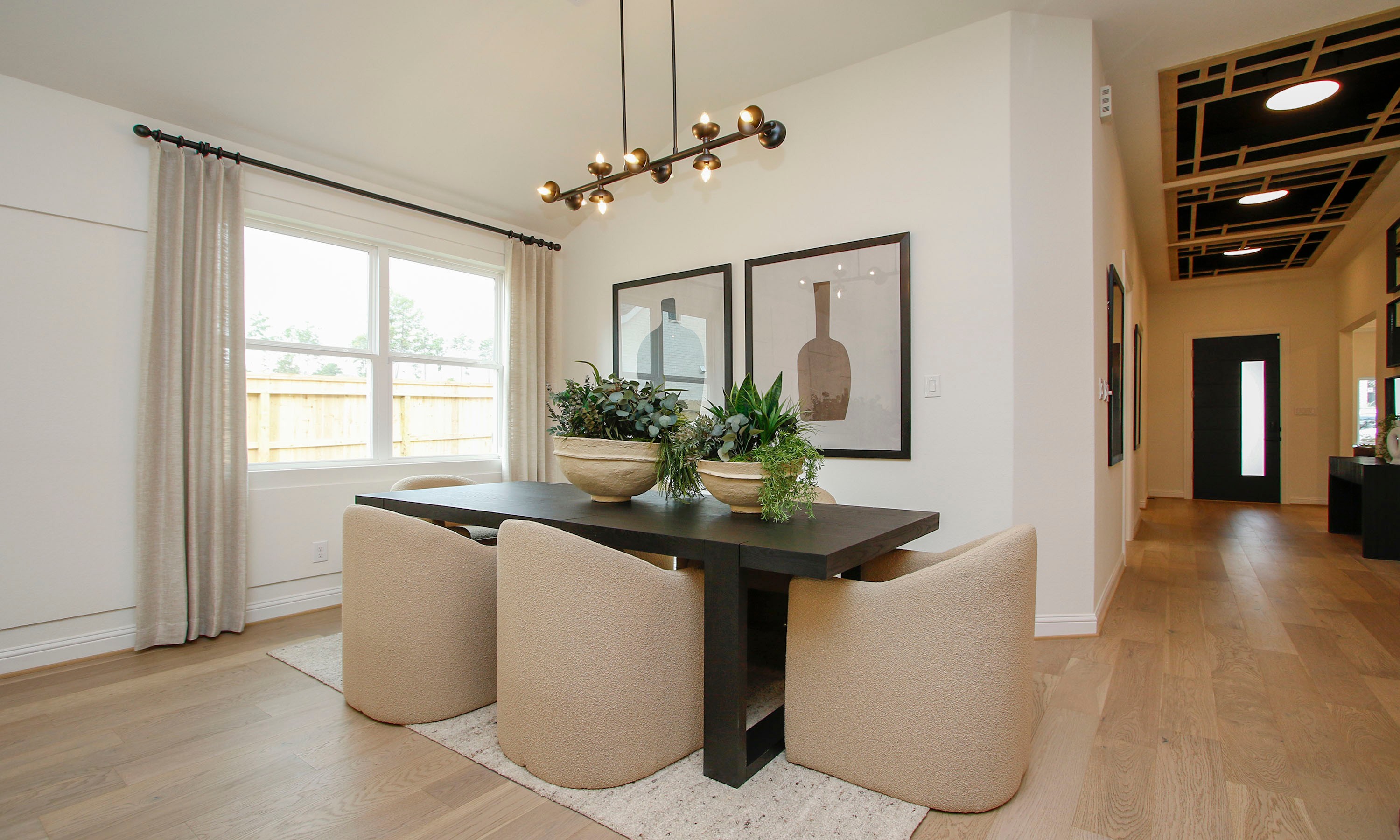 Luxurious Dining Room in The Woodlands Hills with Modern Decor Elegant dining room in The Woodlands Hills. Features modern lighting, beige chairs, large window, and wooden floor.