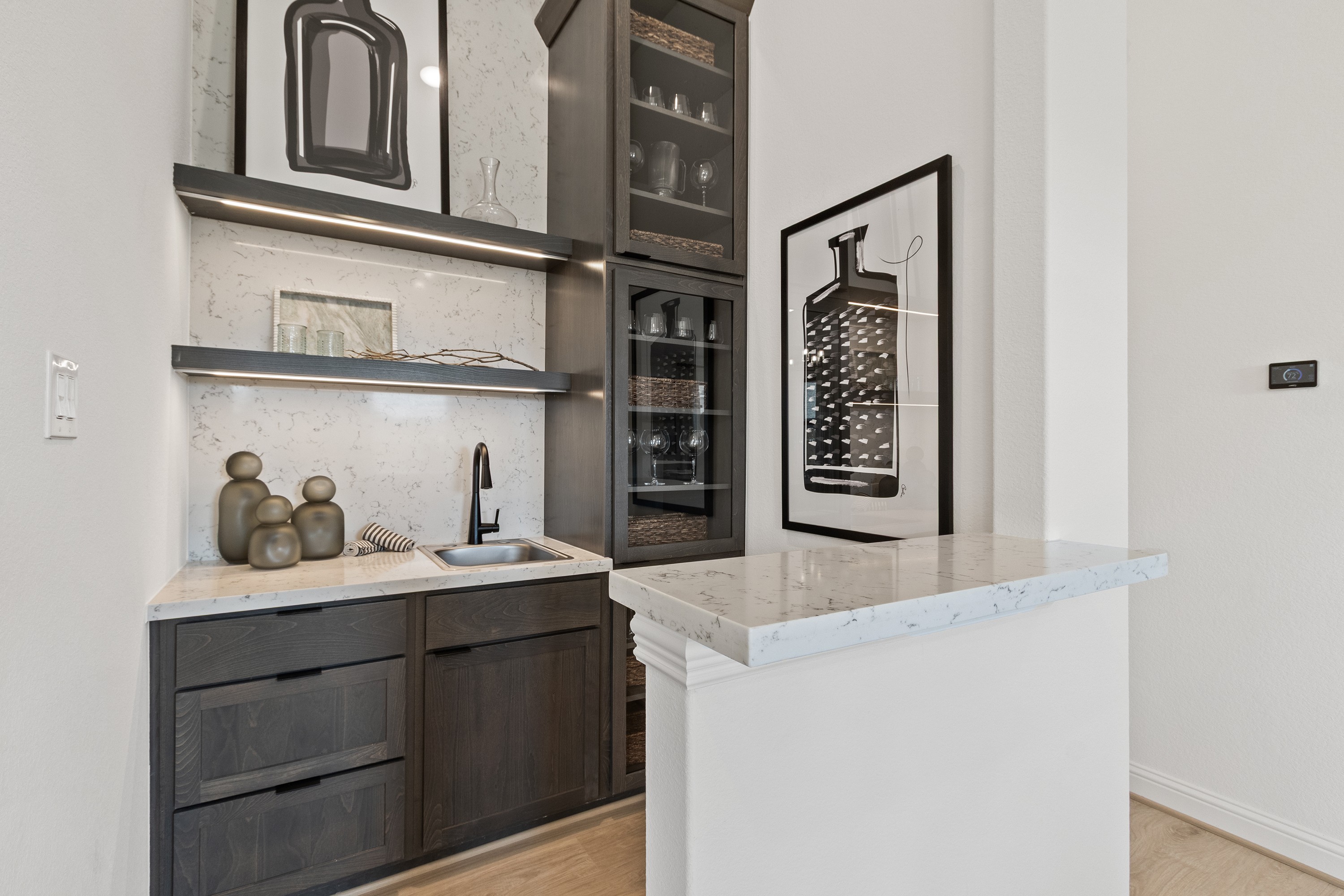 Oakwood Estates Modern Wet Bar with Dark Wood and Marble Wet bar with dark wood cabinets, marble countertop, framed art, located in Oakwood Estates.