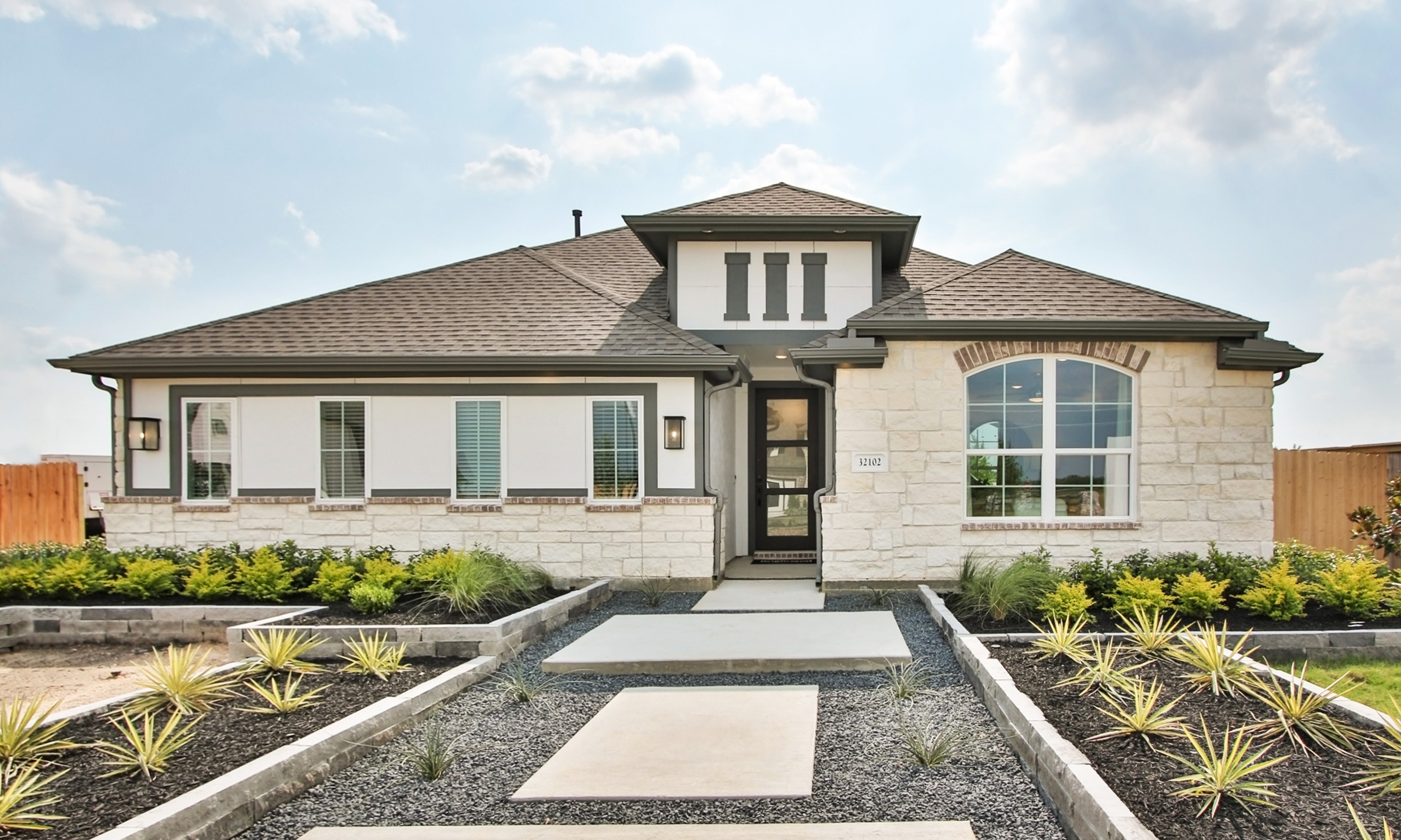 Elegant Stone Facade Home in Oakwood Estates Single-story home with stone facade, large arched window, lush landscaping in Oakwood Estates community.