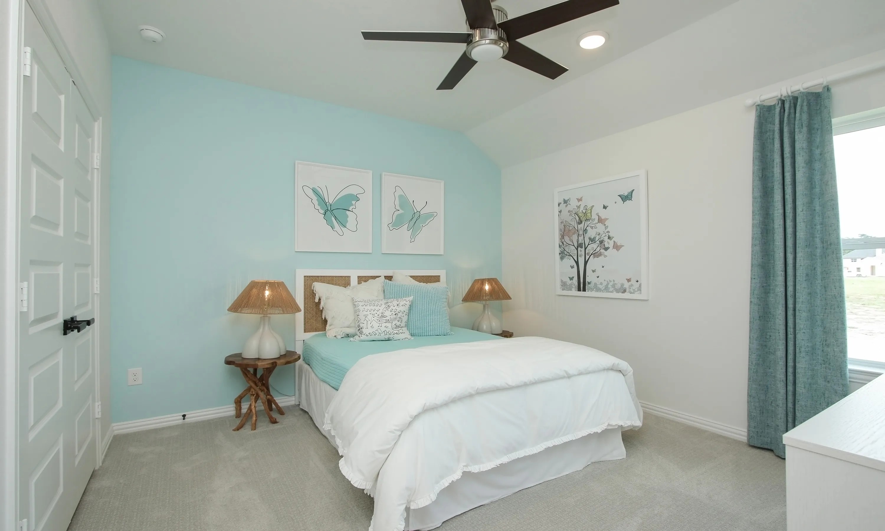 Luxurious Bedroom with Blue Accents in Ellis Cove Community Bedroom with pale blue accent wall in Ellis Cove community; modern fan, butterfly art, and elegant decor.