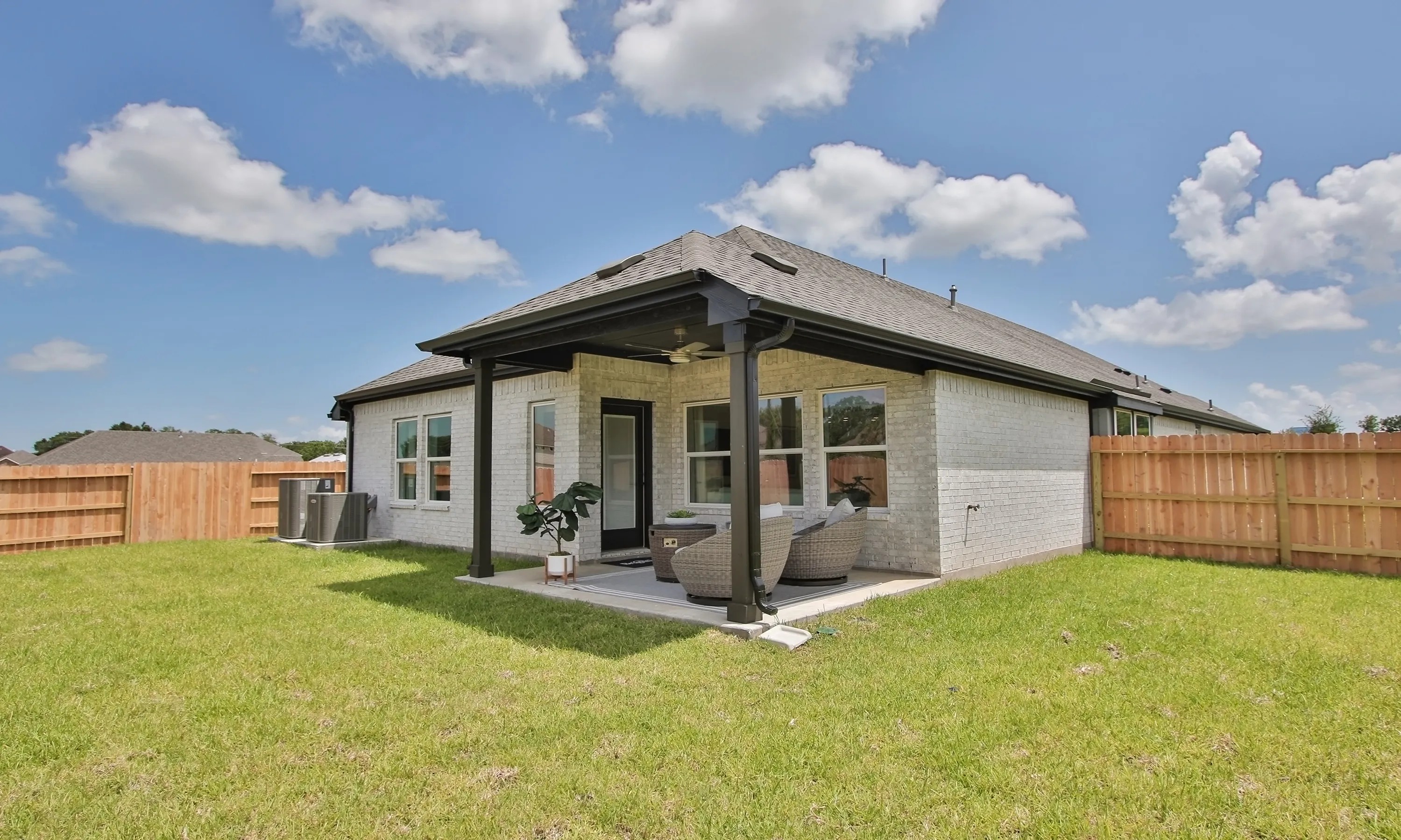 Modern Brick Patio in Ellis Cove with Pergola and Lawn Modern brick patio in Ellis Cove, accented by a sleek pergola and lush lawn, under a vibrant blue sky.