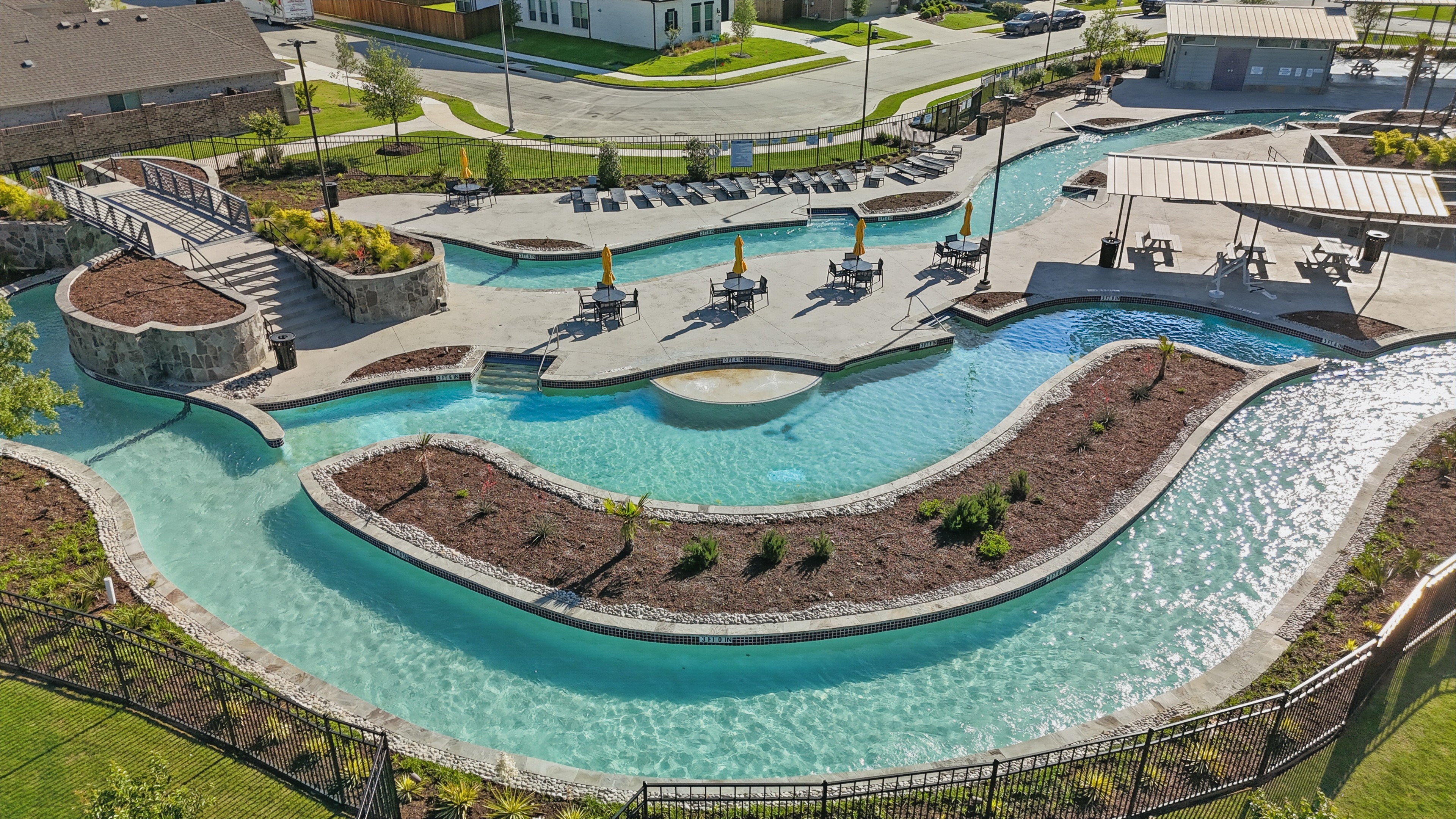 Lazy River and Pool at Wildflower Ranch, Texas Aerial view of a winding lazy river and pool area with umbrellas at Wildflower Ranch community, Texas.