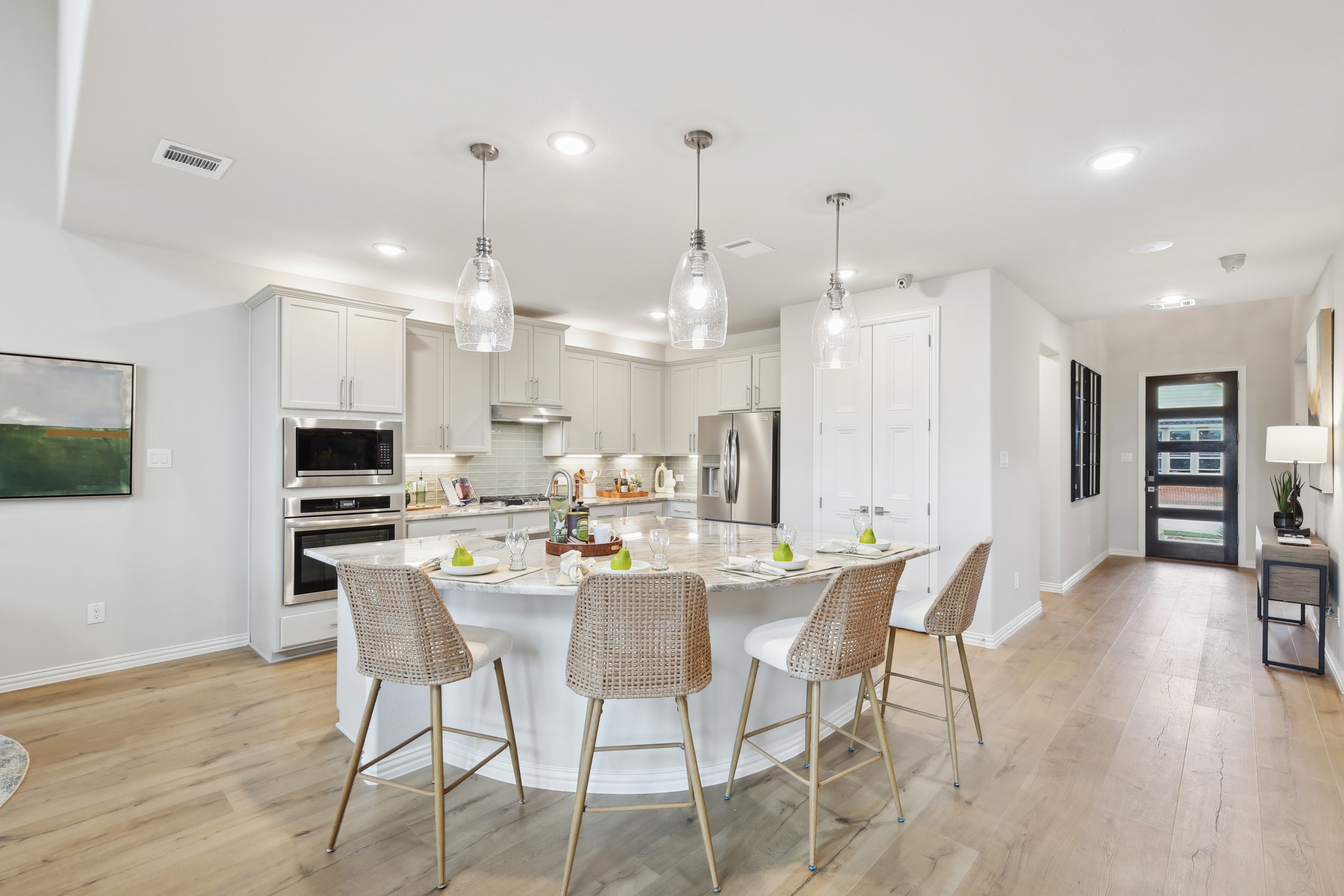 Modern Kitchen Design in Wildflower Ranch Home Luxury kitchen with marble island, pendant lights, and wicker stools in Wildflower Ranch.
