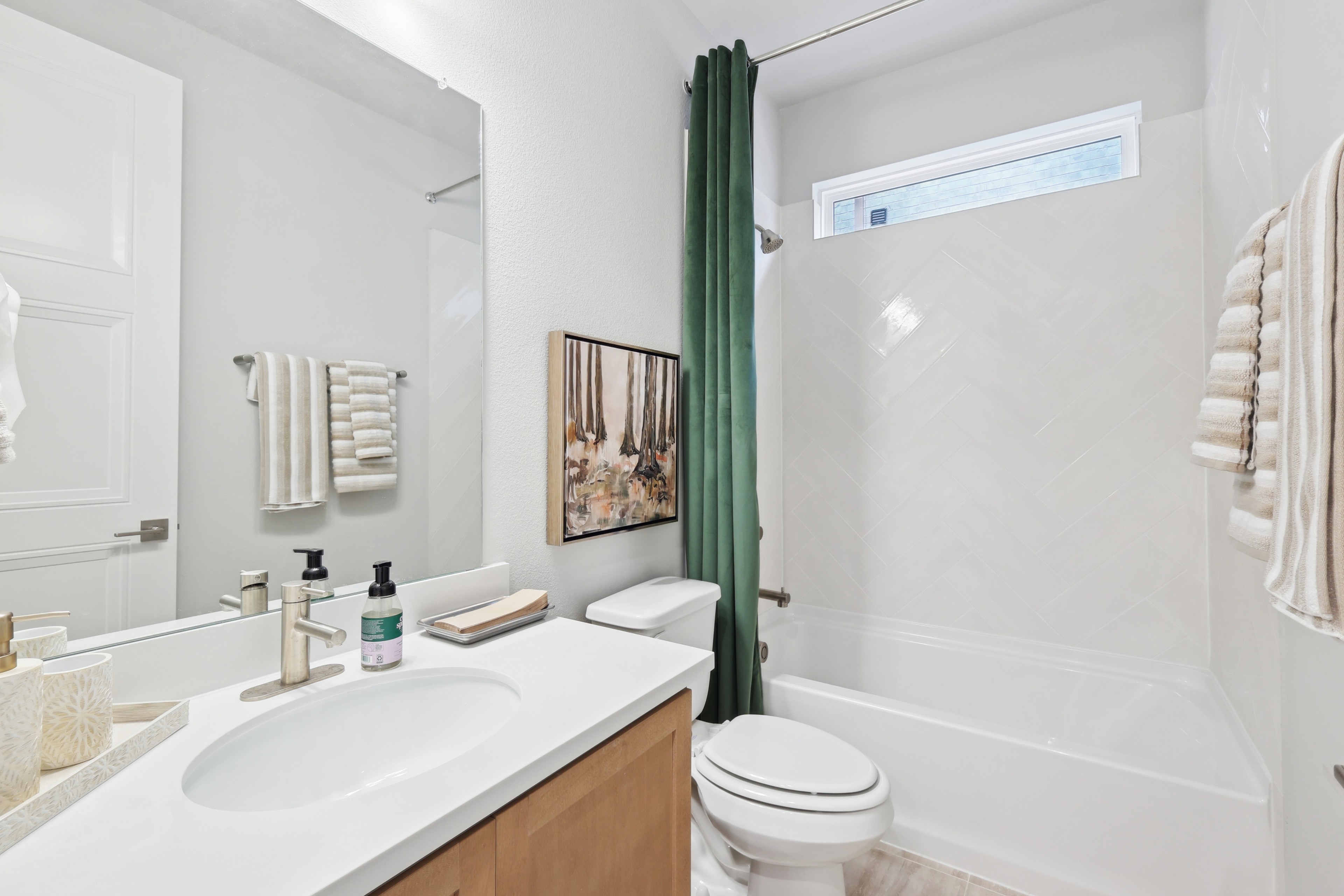 Modern Bathroom with Herringbone Tiles at Wildflower Ranch Elegant bathroom with modern vanity, herringbone tiles, art, Wildflower Ranch, spacious design.