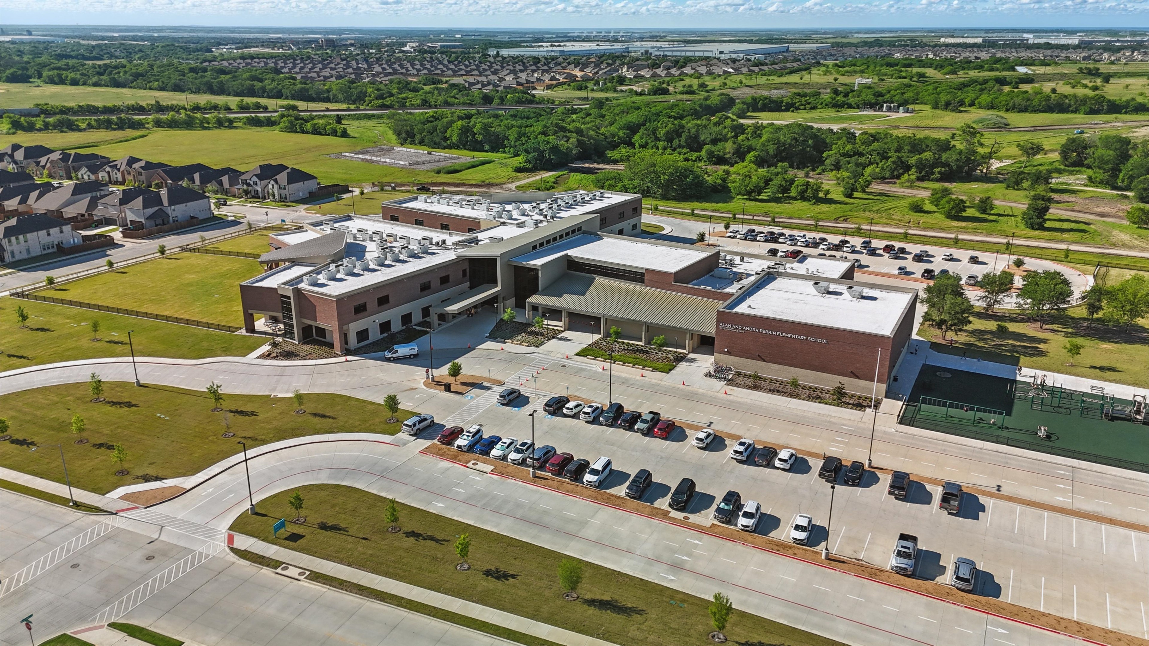 Aerial View of Modern School in Wildflower Ranch Community Aerial view of modern school building with parking, surrounded by greenery in Wildflower Ranch community.