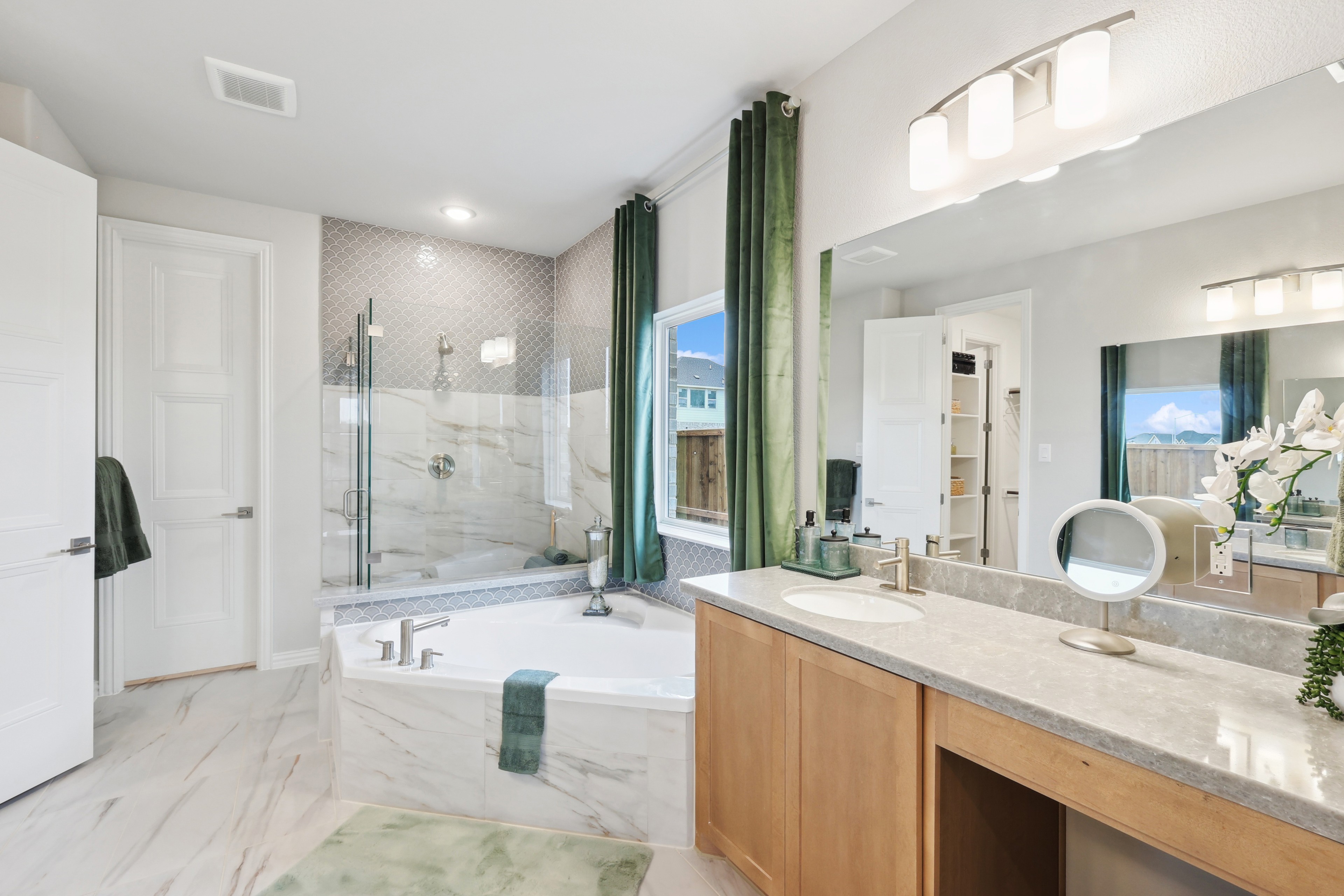 Elegant Bathroom with Marble Tile at Wildflower Ranch Luxurious bathroom with marble tile, dual vanity, and soaking tub at Wildflower Ranch, featuring large window and green accents.