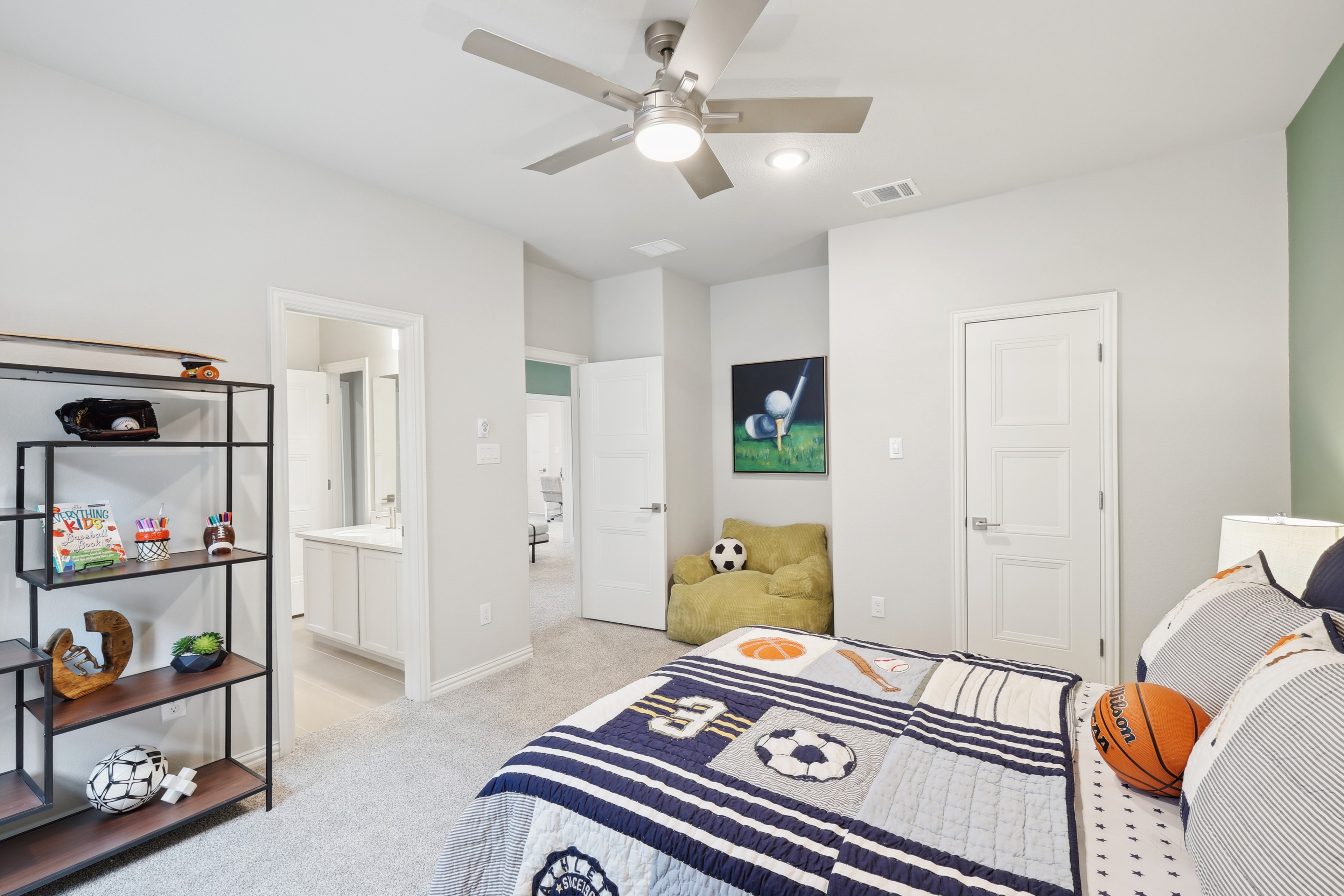 Sports-Themed Kids Bedroom in Wildflower Ranch with Ensuite Modern children's bedroom with sports theme, sleek ceiling fan, plush carpet, and ensuite bathroom in Wildflower Ranch.