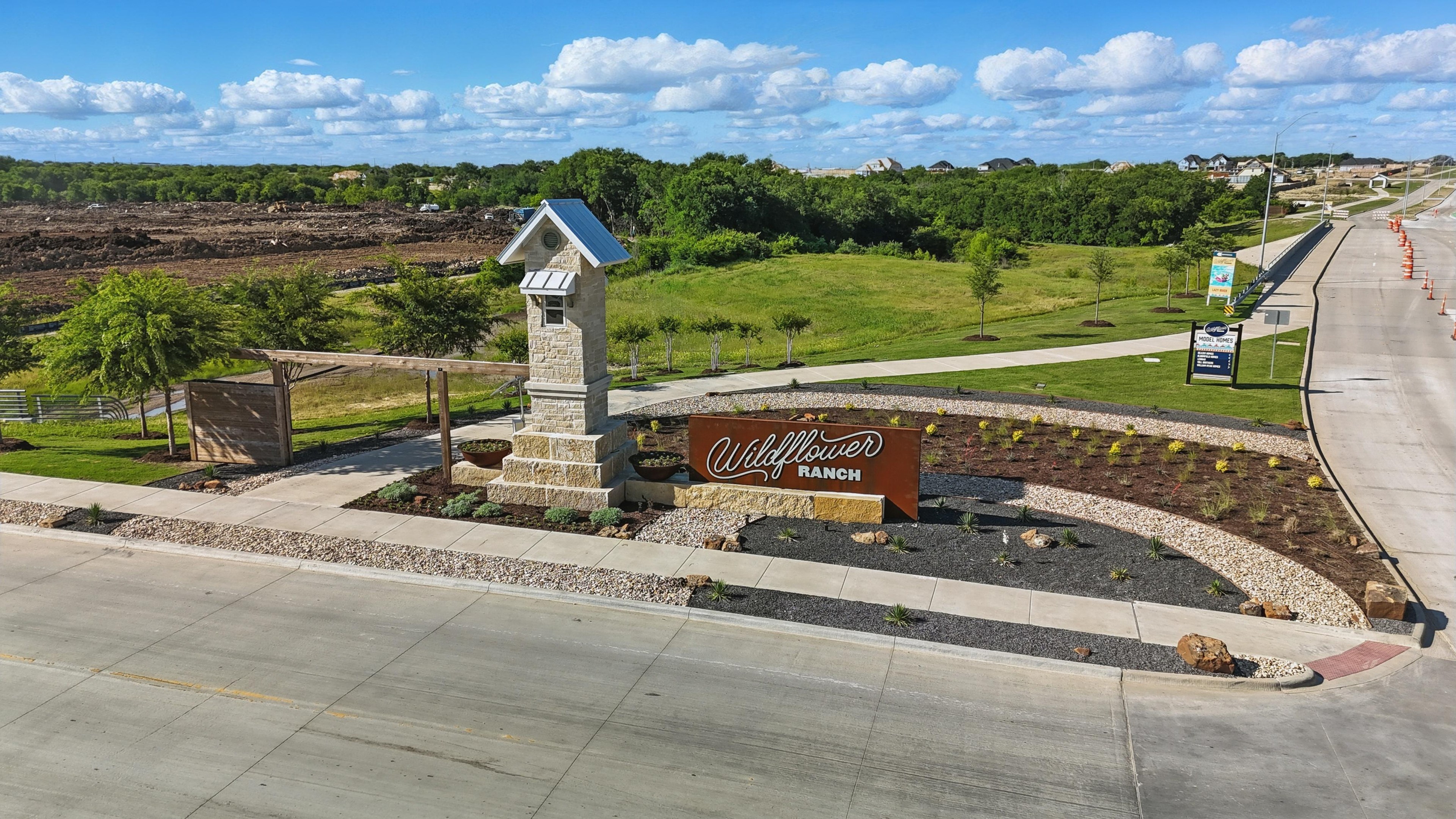 Wildflower Ranch Entrance, Fort Worth | Stone Pillar & Landscaping Entrance to Wildflower Ranch, Fort Worth; stone pillar, landscaping, clear skies, rural setting.