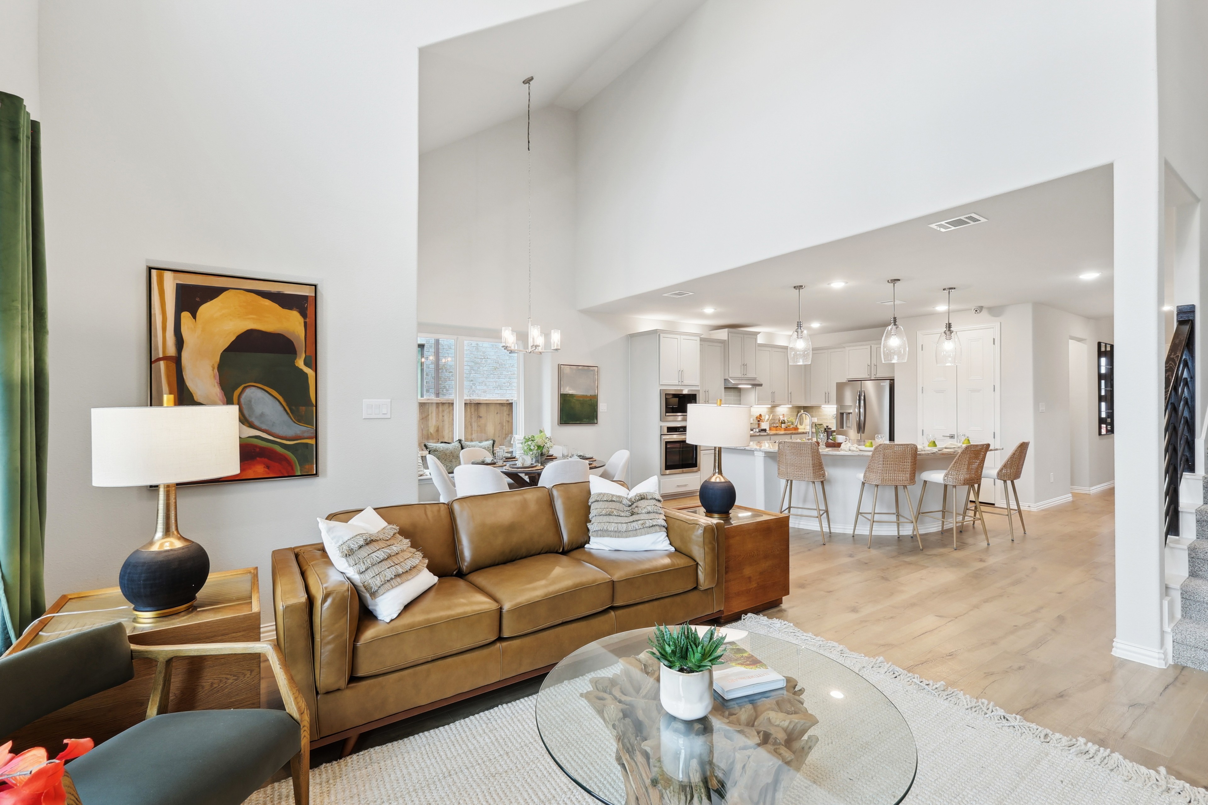 Open-Concept Living Space with Vaulted Ceiling at Wildflower Ranch Stylish open-concept living area with vaulted ceiling, leather sofa, modern kitchen, in Wildflower Ranch.