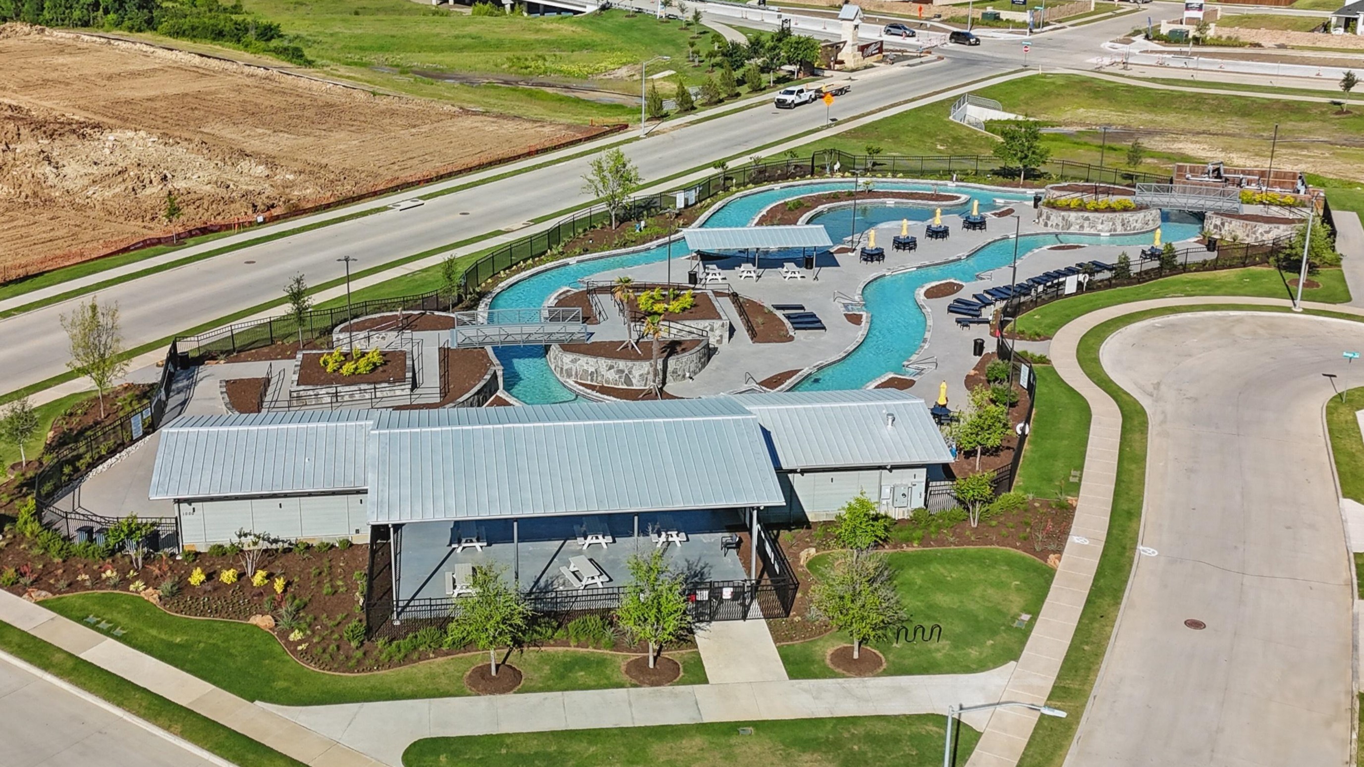 Wildflower Ranch Community Leisure Pool, Texas Aerial view of Wildflower Ranch community's leisure pool with modern pavilions and green landscaping, Texas.