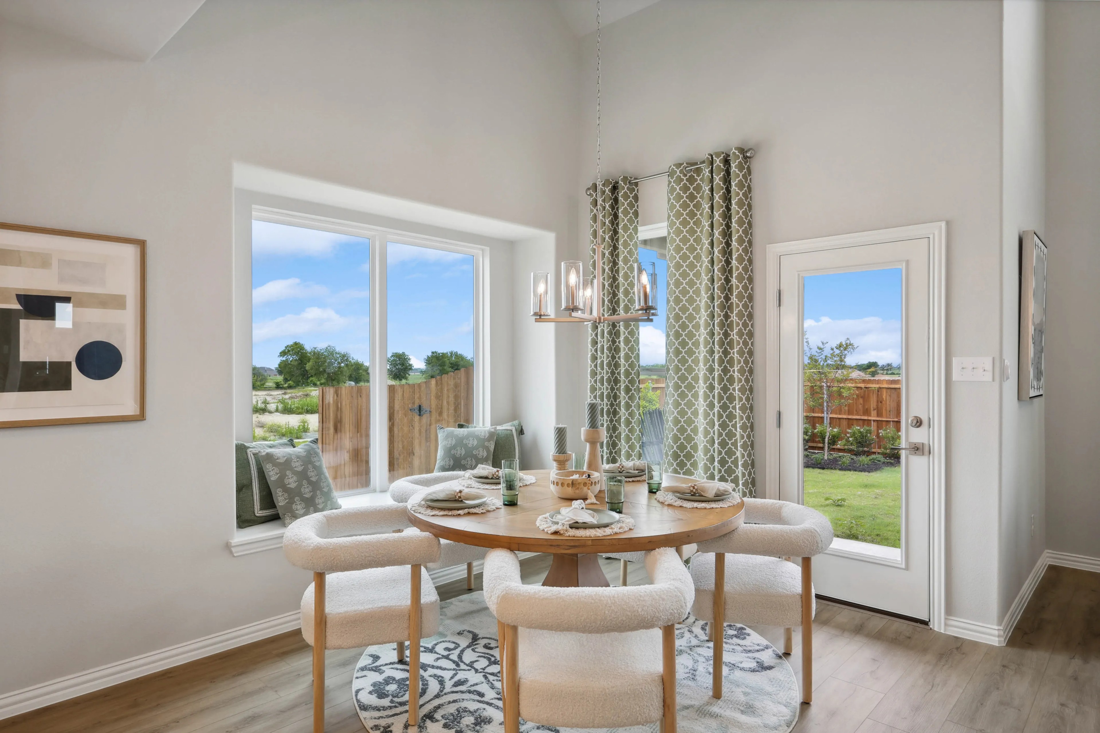 Dining Area with Garden View in Hulen Trails Community Dining area with round wooden table, plush chairs, large windows, elegant chandelier, and garden view in Hulen Trails.