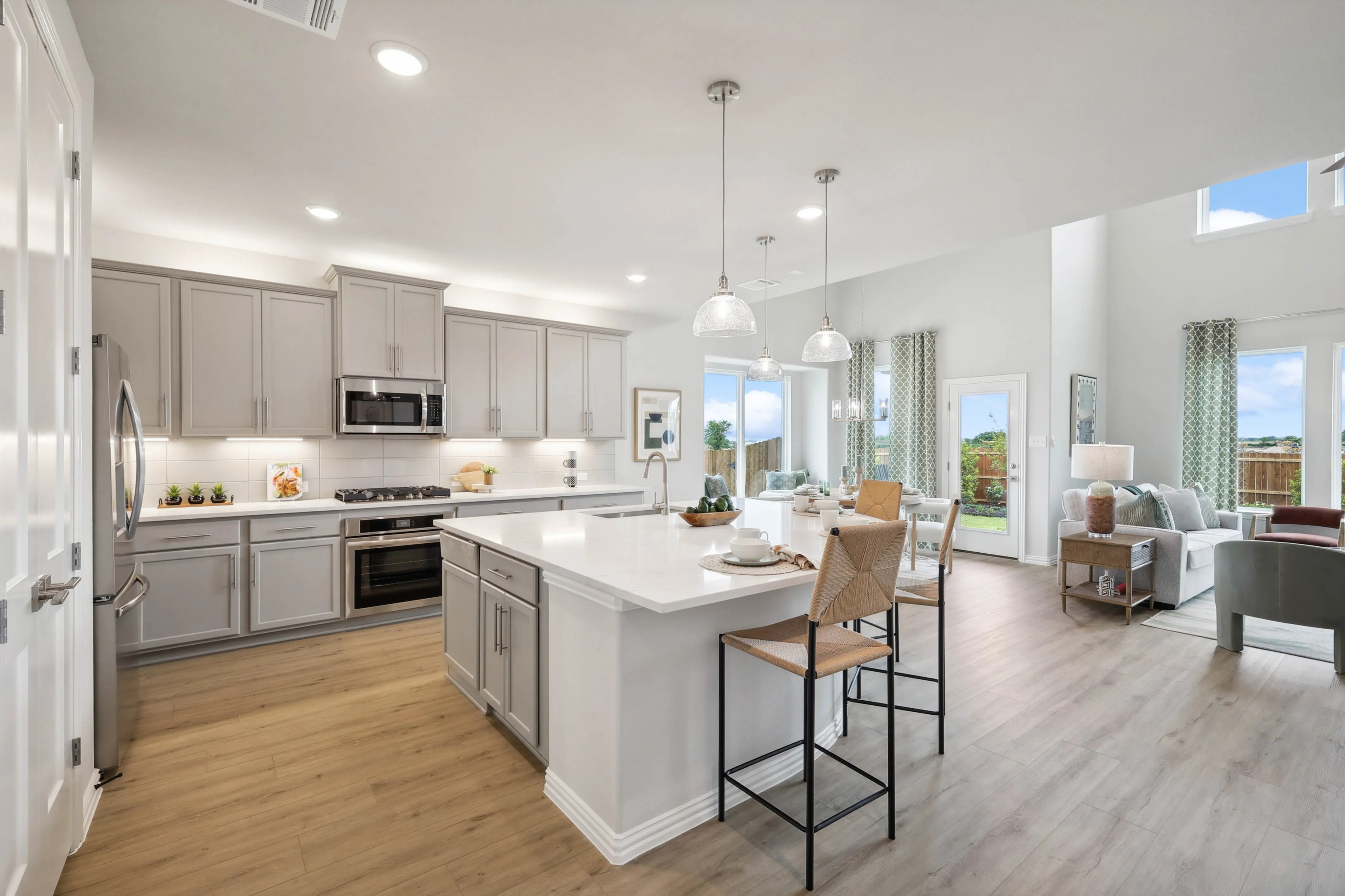 Modern Kitchen in Open Floor Plan at Hulen Trails, Fort Worth, Texas Modern kitchen with light gray cabinets, large white island, open floor plan in Hulen Trails, Fort Worth, Texas.