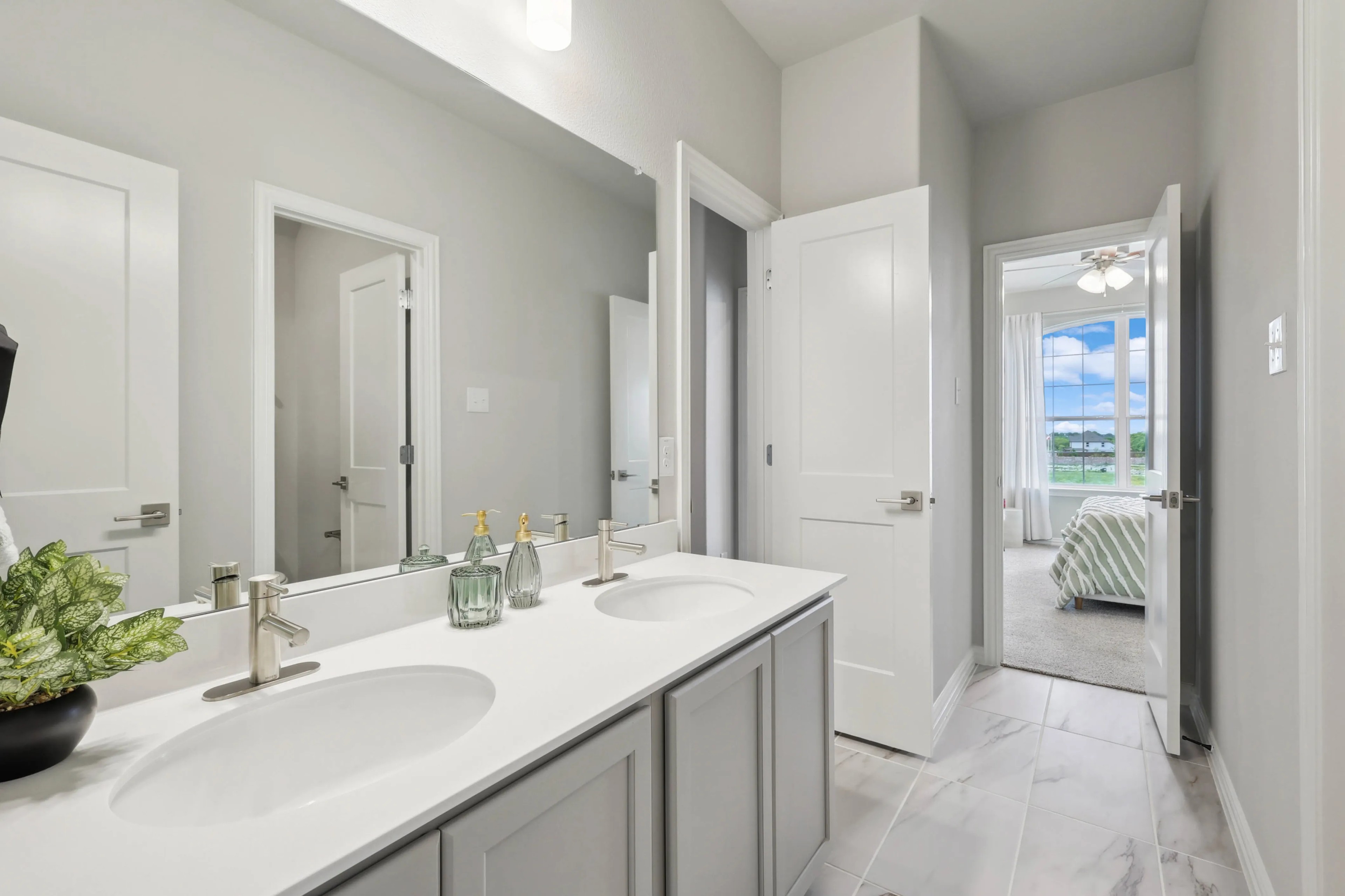 Elegant Double Vanity Bathroom in Hulen Trails Community Modern bathroom with double vanity, sleek fixtures, adjacent bedroom view, Hulen Trails home.
