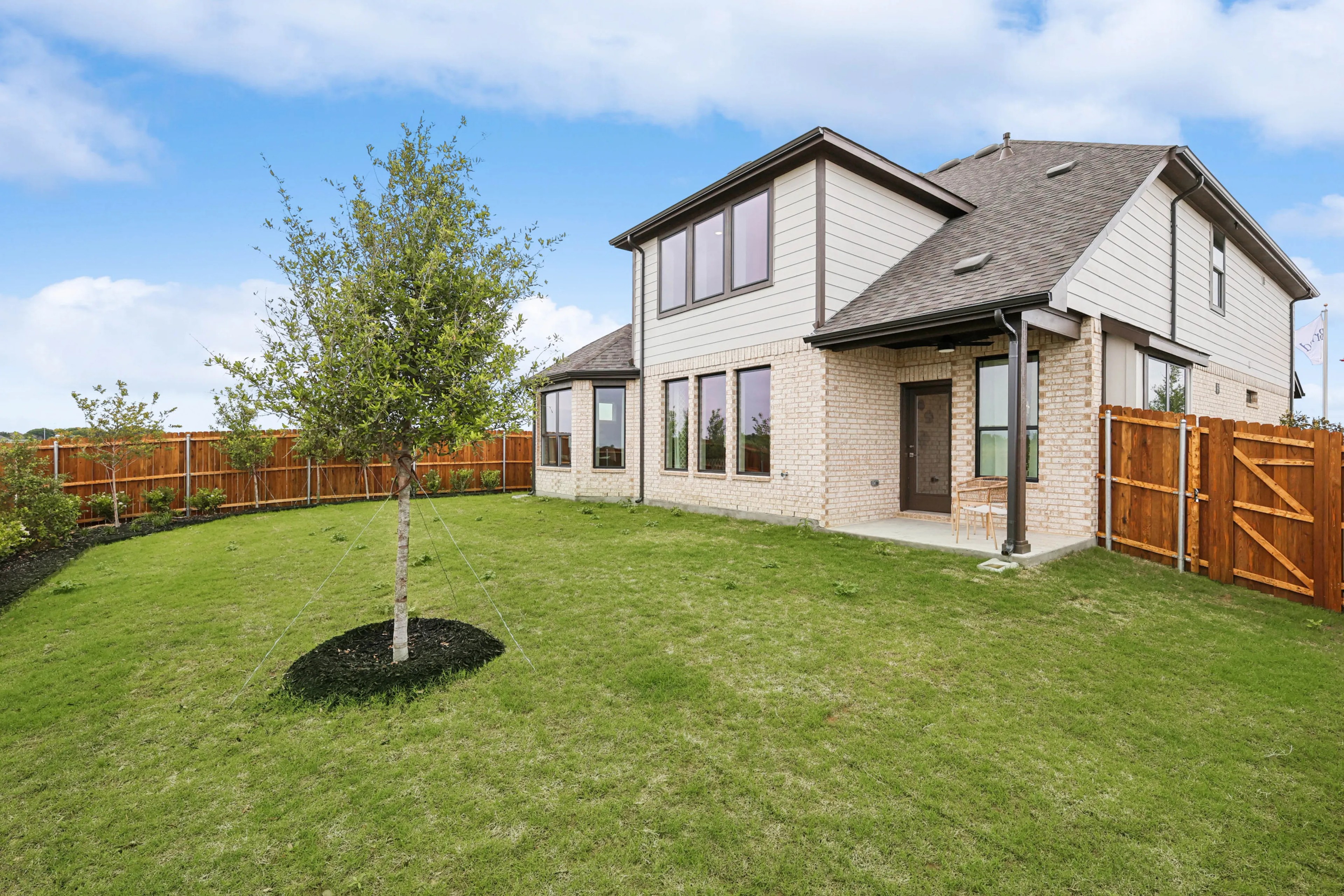 Two-Story Brick Home in Hulen Trails with Spacious Yard Two-story brick house in Hulen Trails with large windows, patio, and landscaped yard.