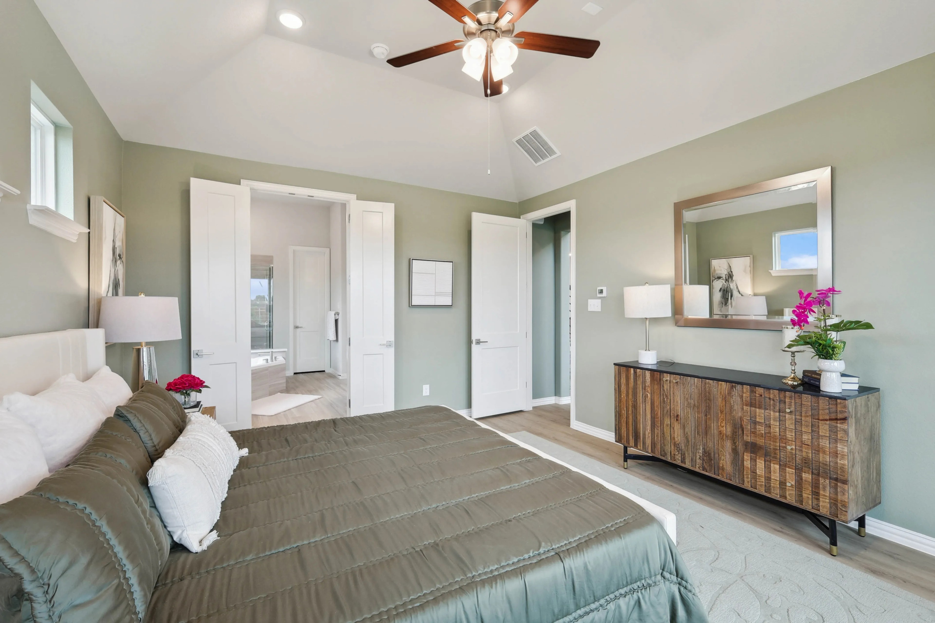 Elegant Bedroom with En-Suite Bath in Hulen Trails Community Spacious bedroom with green walls, wood accents, and en-suite bath in Hulen Trails. Features ceiling fan and modern decor.
