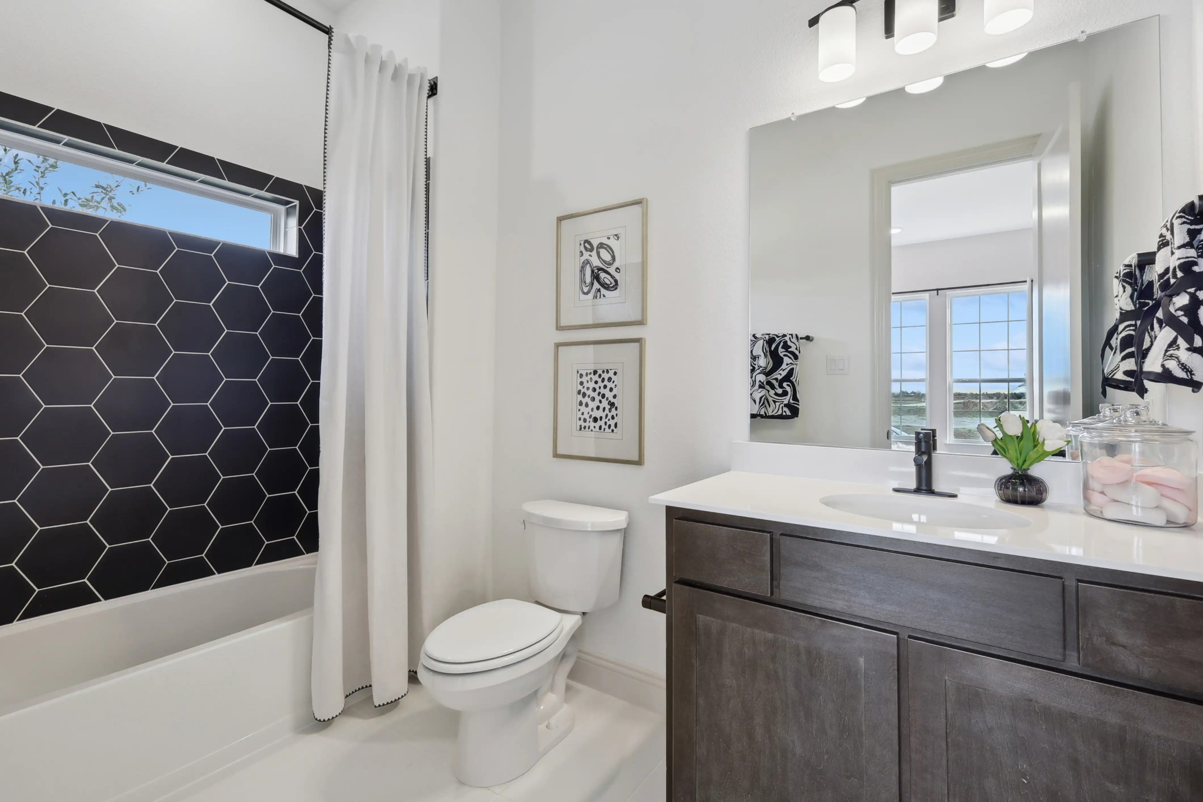Luxurious Bathroom with Hexagonal Tile in Westside Preserve Modern bathroom with hexagonal black tile, sleek vanity, large window; Westside Preserve.