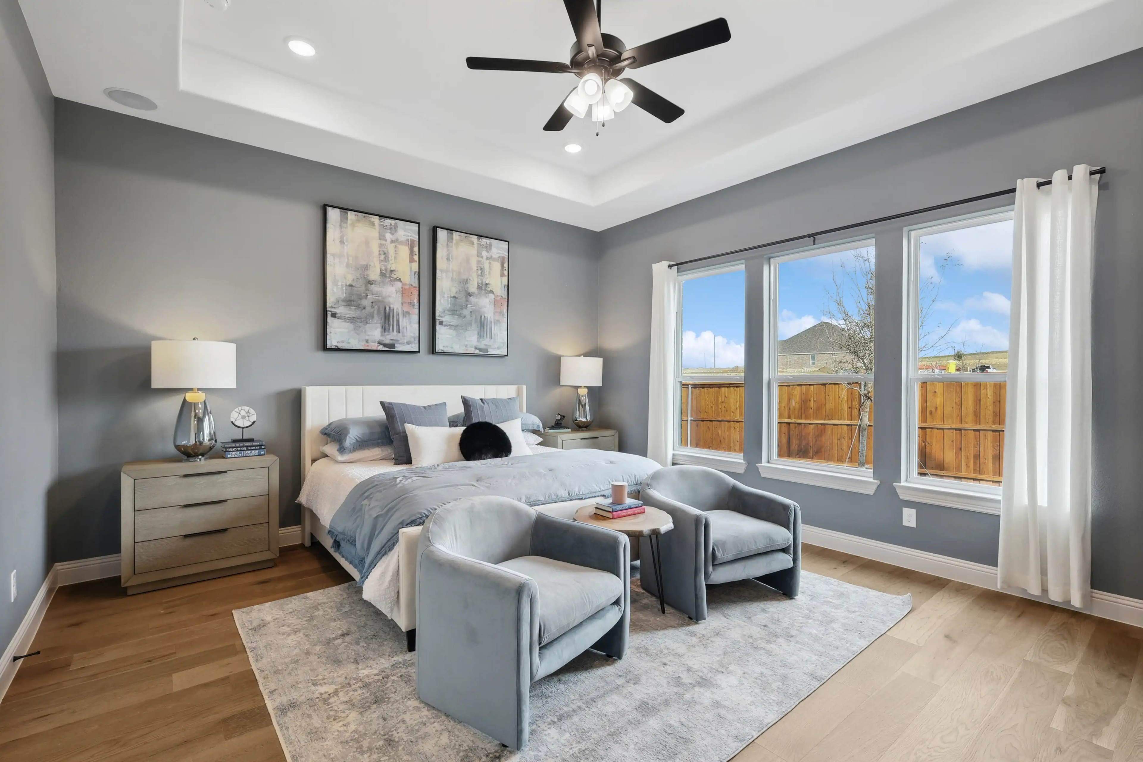 Westside Preserve Bedroom Interior Design with Modern Decor Luxury bedroom with gray walls, tray ceiling, modern furniture, and large windows at Westside Preserve.
