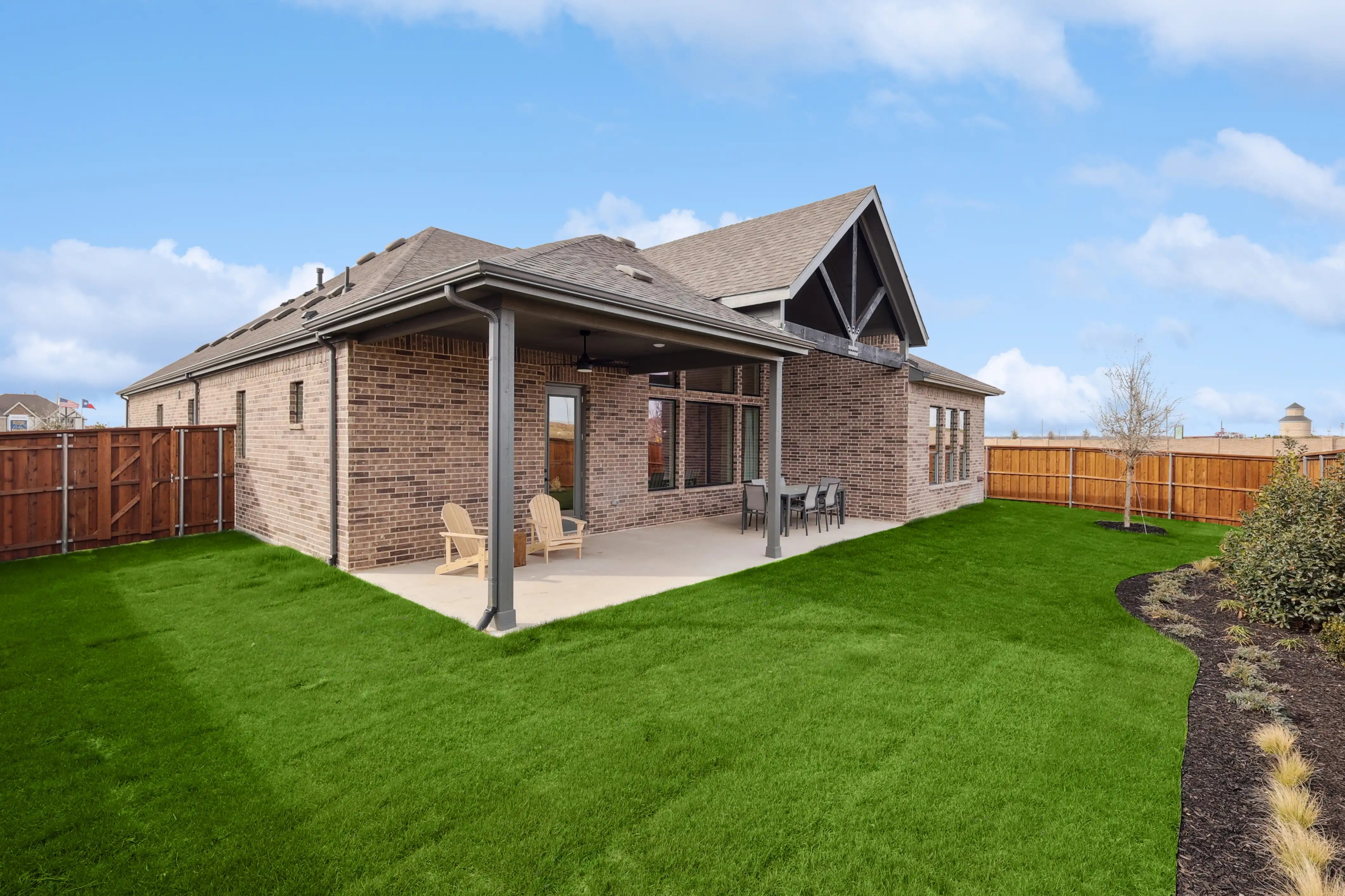 Westside Preserve Brick House, Gabled Roof, Elegant Backyard Brick house with gabled roof, covered patio, and lush garden in Westside Preserve, showcasing suburban architecture.