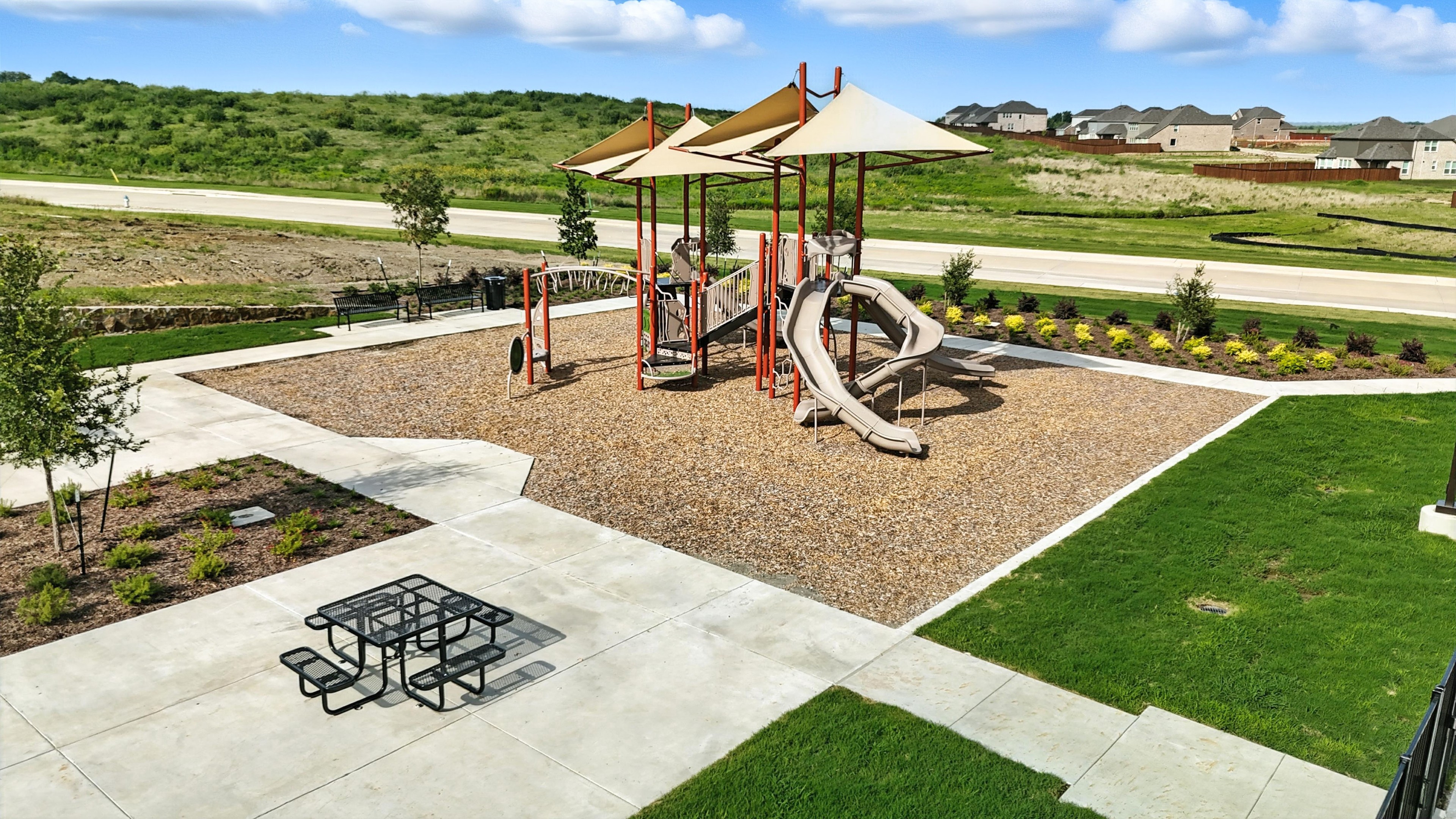 Westside Preserve Playground with Modern Shade Structures Playground with slides, shade structures, in Westside Preserve community; open green landscape, nearby road.