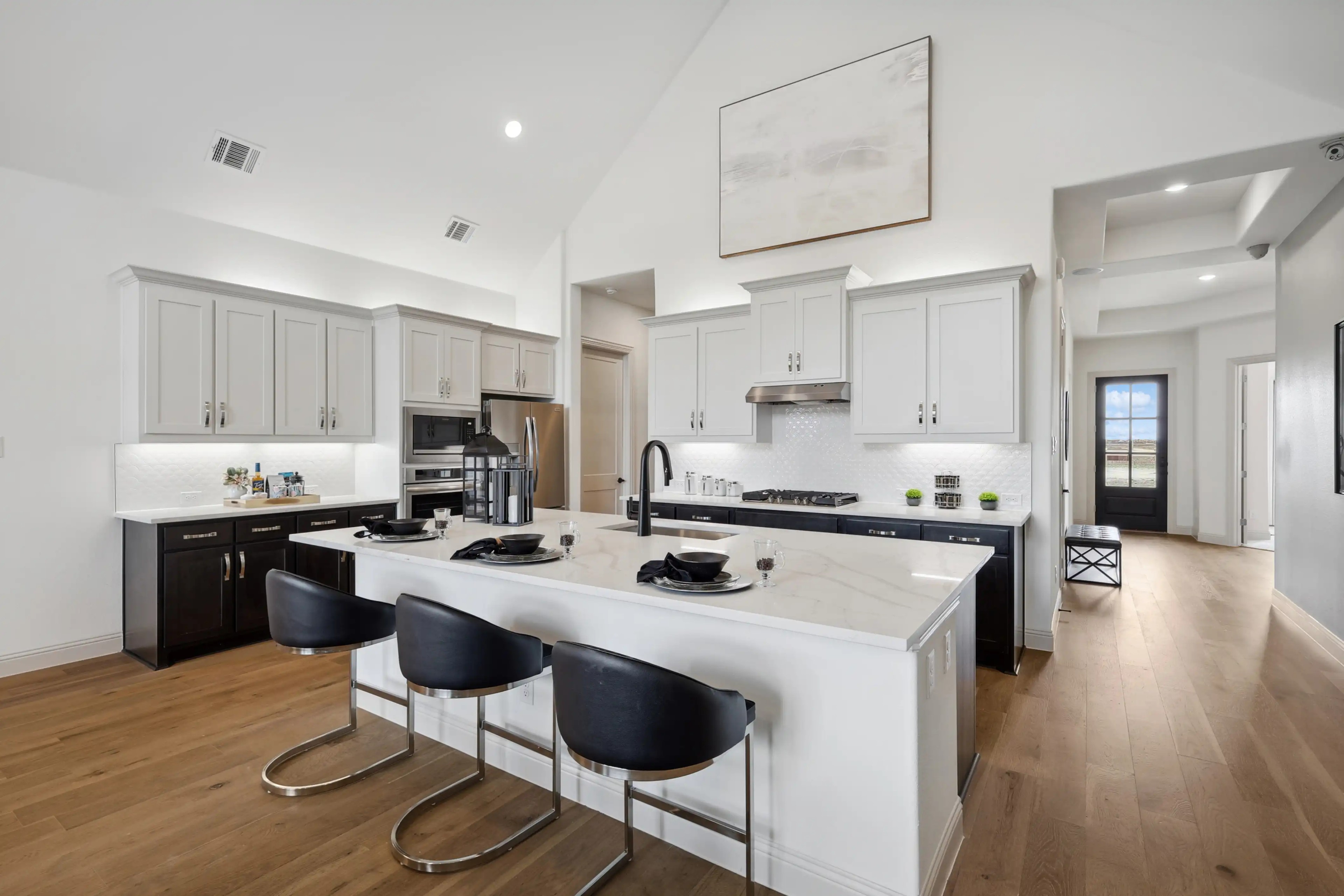 Luxury Kitchen in Westside Preserve Home with Marble Island and Hardwood Floors Luxury kitchen with white cabinets, marble island, hardwood floors, and stainless appliances in Westside Preserve home.