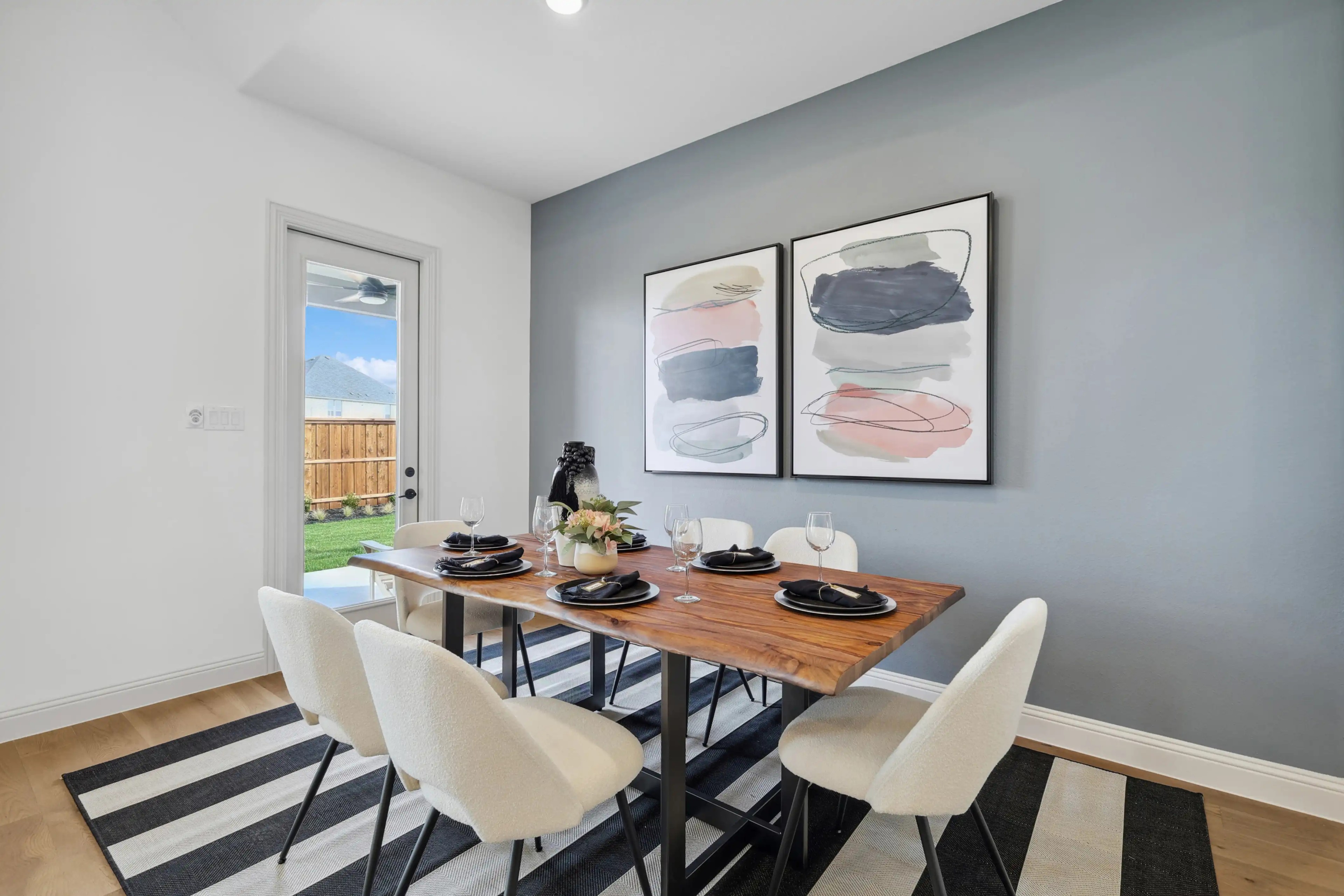 Dining Room with Abstract Art in Westside Preserve Home Elegant dining area with wooden table, abstract art, and outdoor view in Westside Preserve home.