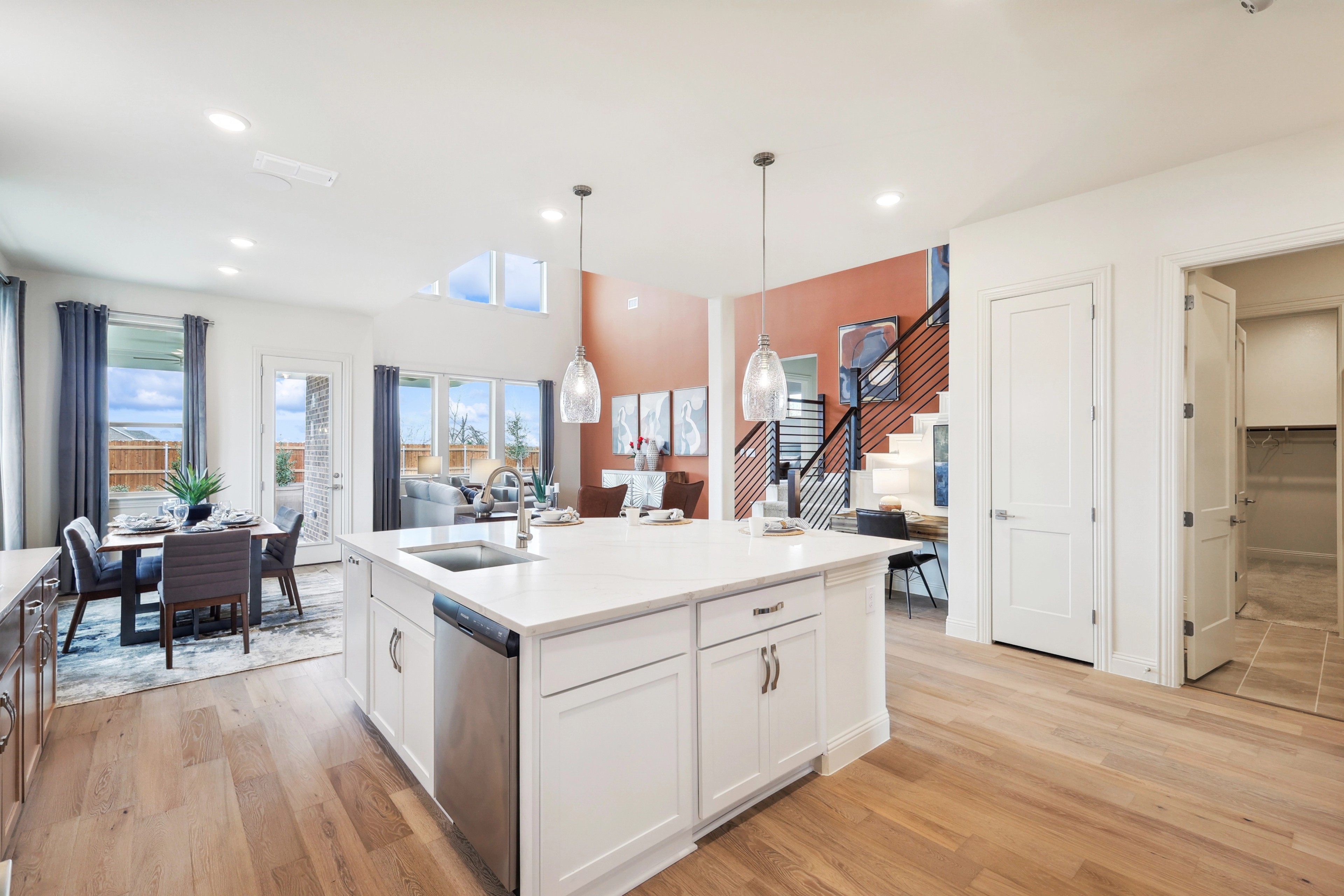 Elegant Open Kitchen with Island in The Oaks Community Real Estate Modern kitchen with white island, pendant lights, open layout, wood floors in The Oaks community. Bright and spacious.