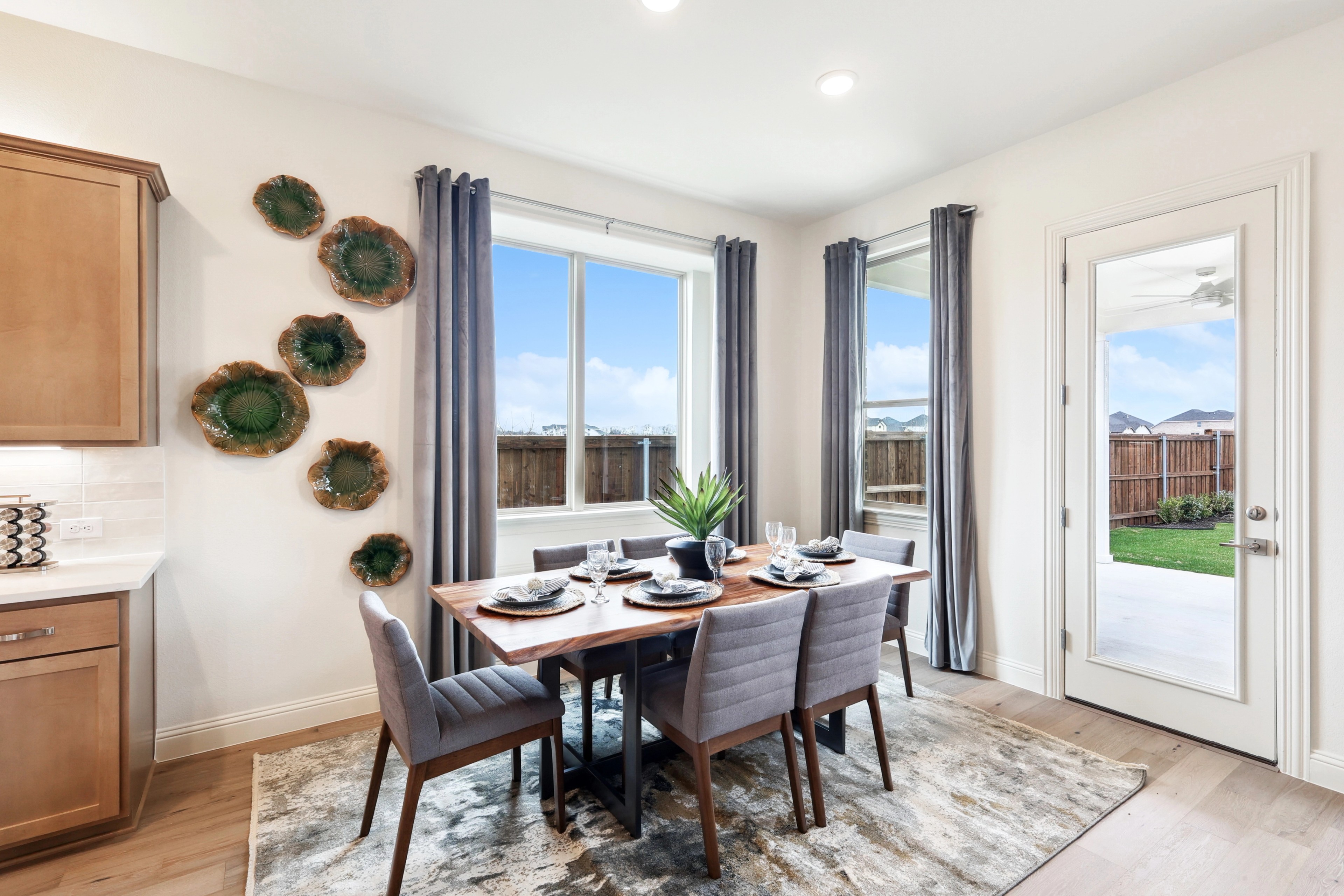 Dining Room with Wooden Table and Wall Art in The Oaks Community Elegant dining room features a wooden table, gray chairs, large windows, and wall art in The Oaks community.