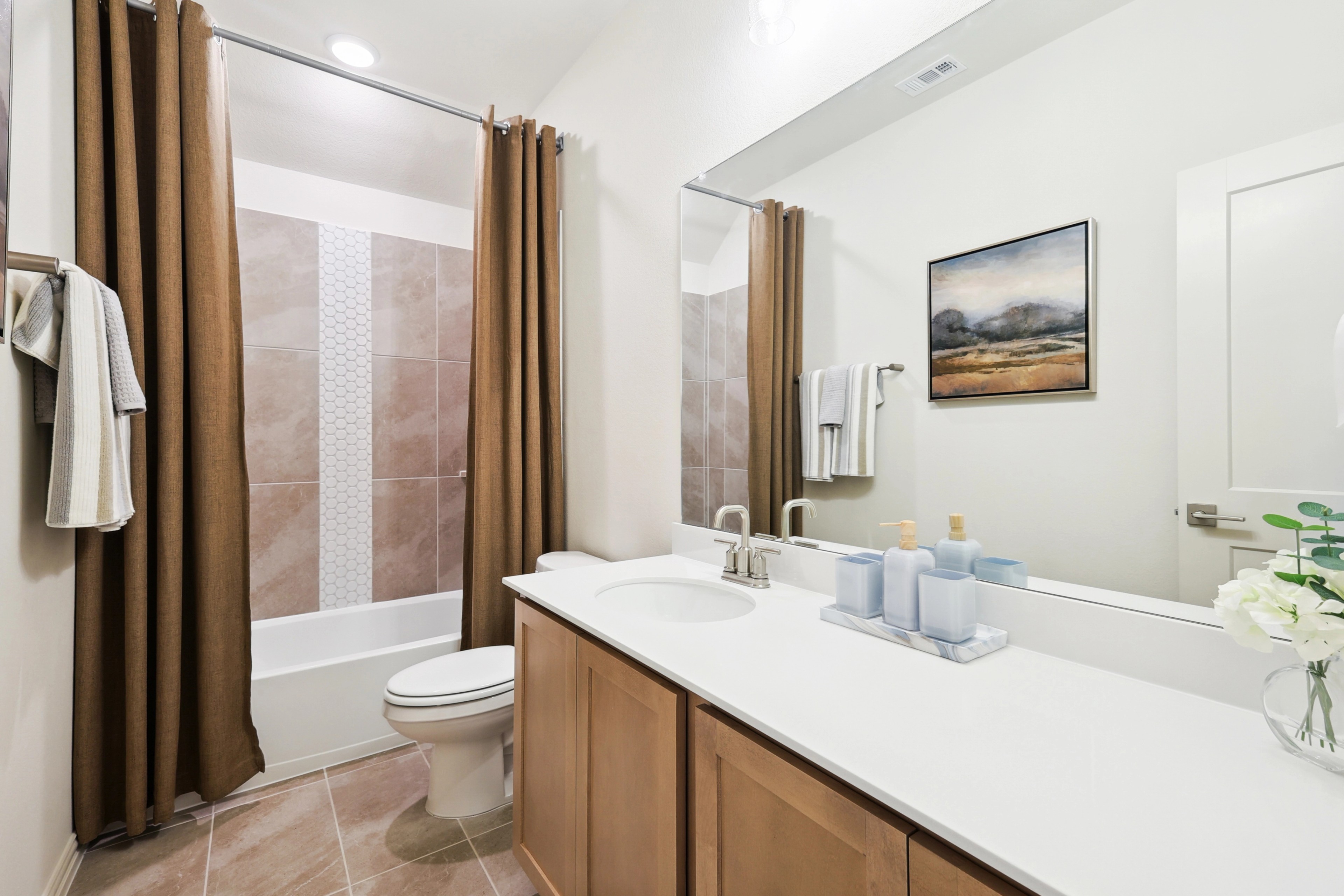 Modern Bathroom Design in The Oaks Community Modern bathroom with wood vanity, art piece, and tiled shower in The Oaks community.