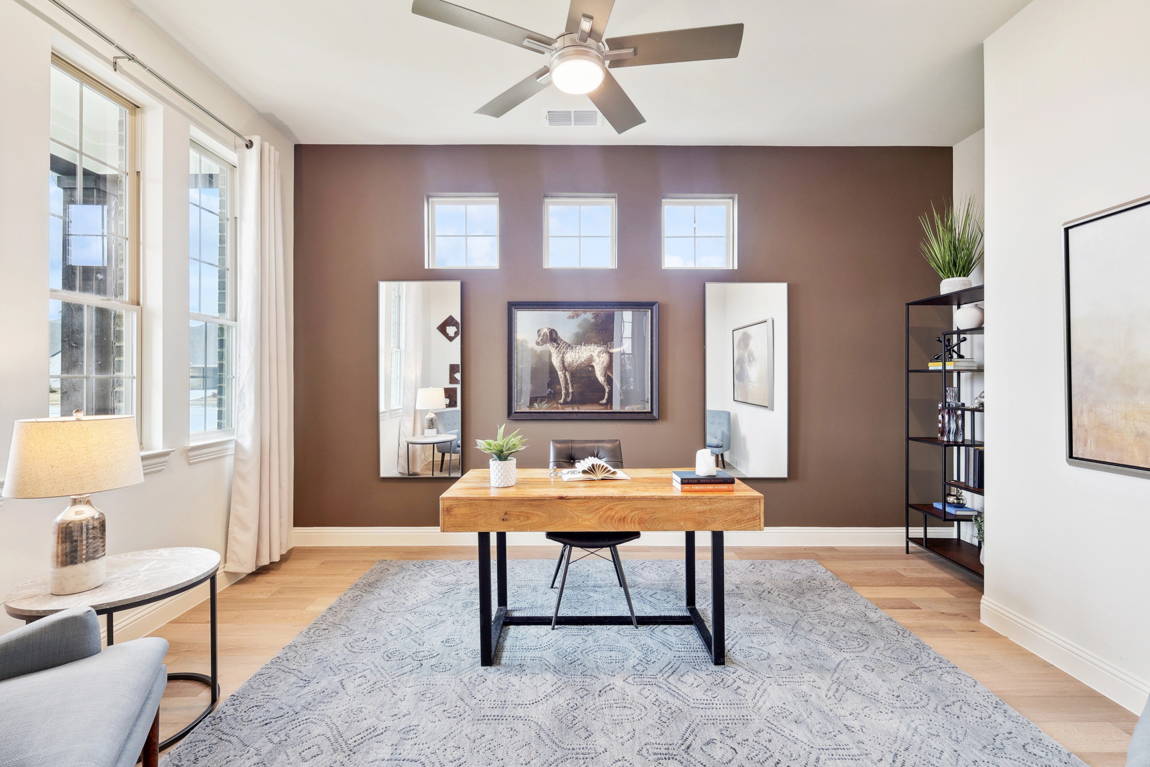 Modern Office Design in The Oaks with Wooden Desk and Large Windows Modern home office with wood desk, abstract art, large windows, ceiling fan in The Oaks community.