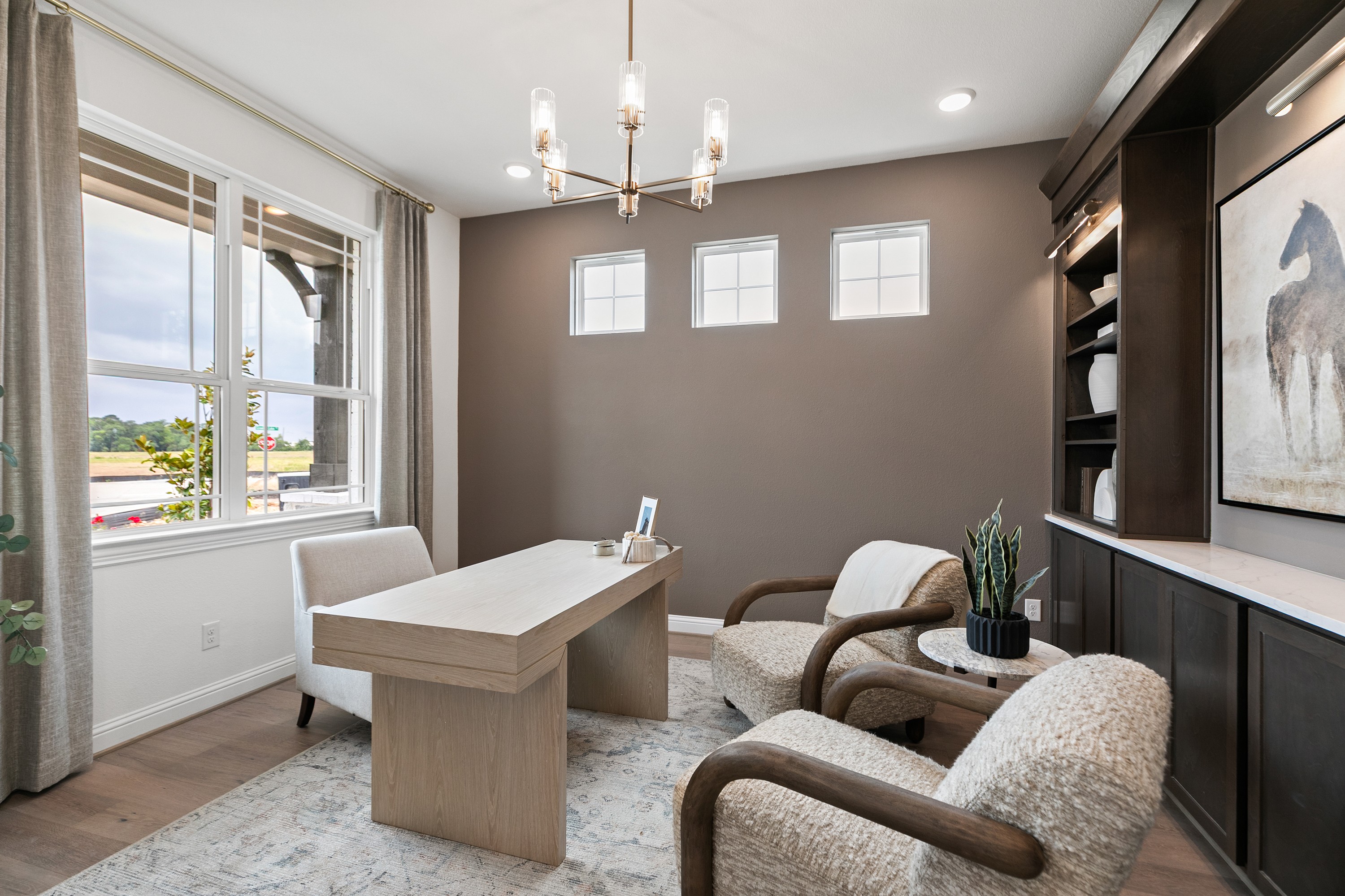Sophisticated Study Room in Katy Lakes Community with Modern Design Elegant study with natural light, plush seating, wood desk, and built-in shelves in Katy Lakes community.