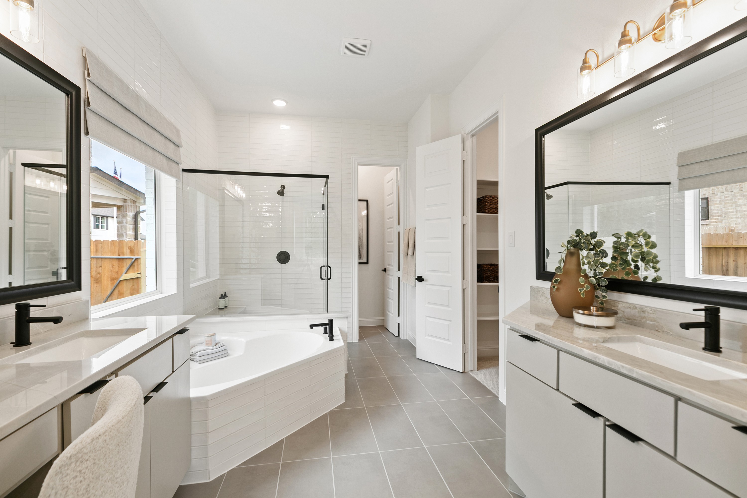 Luxurious Bathroom with Freestanding Tub in Katy Lakes Community Elegant bathroom in Katy Lakes community, featuring dual vanities, freestanding tub, glass shower, and large mirrors.