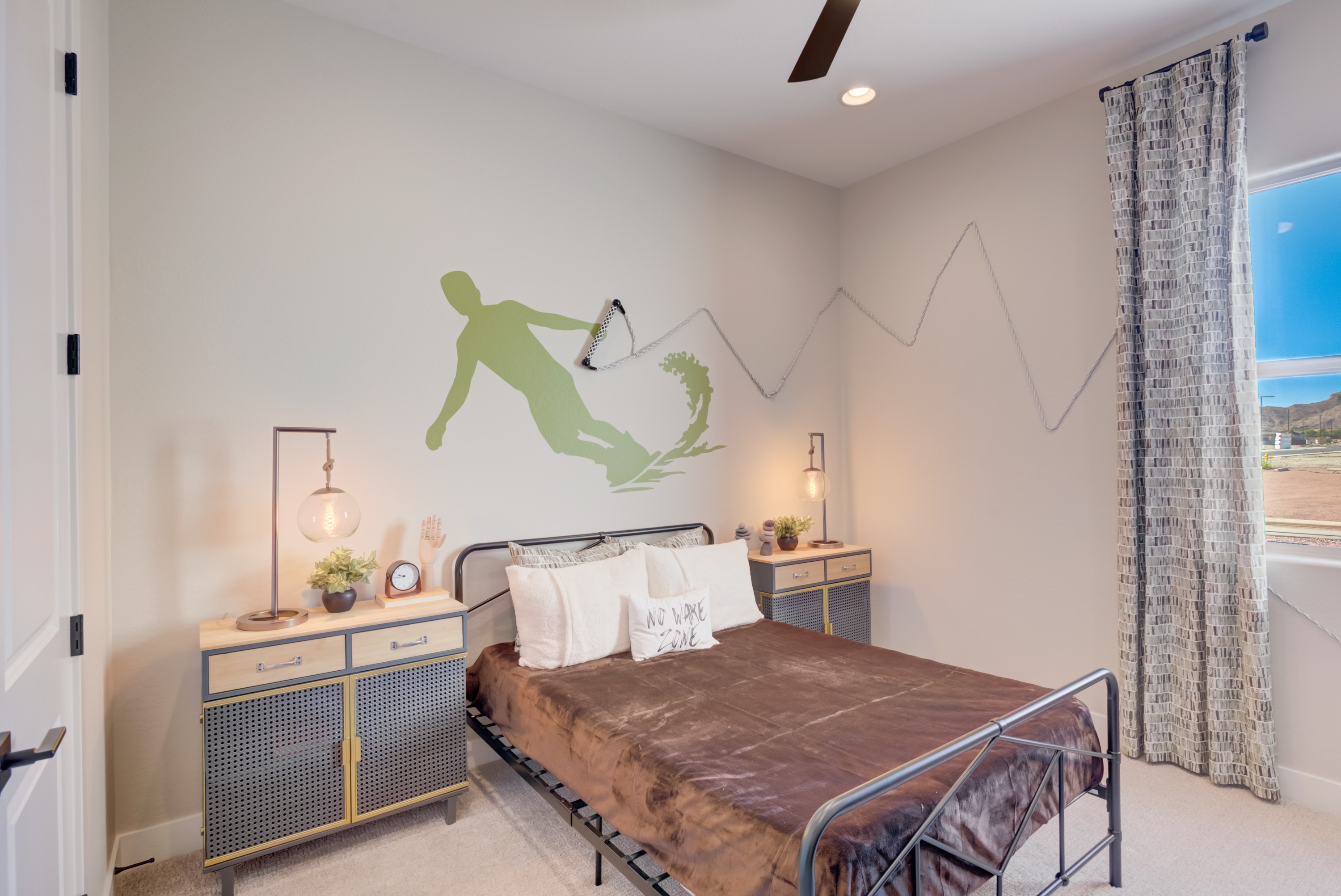 Surfer-Themed Bedroom Decor in Arroyo Seco's Palazzo Community Bedroom with surfer wall decor, stylish nightstands, and window. Arroyo Seco, Palazzo community.